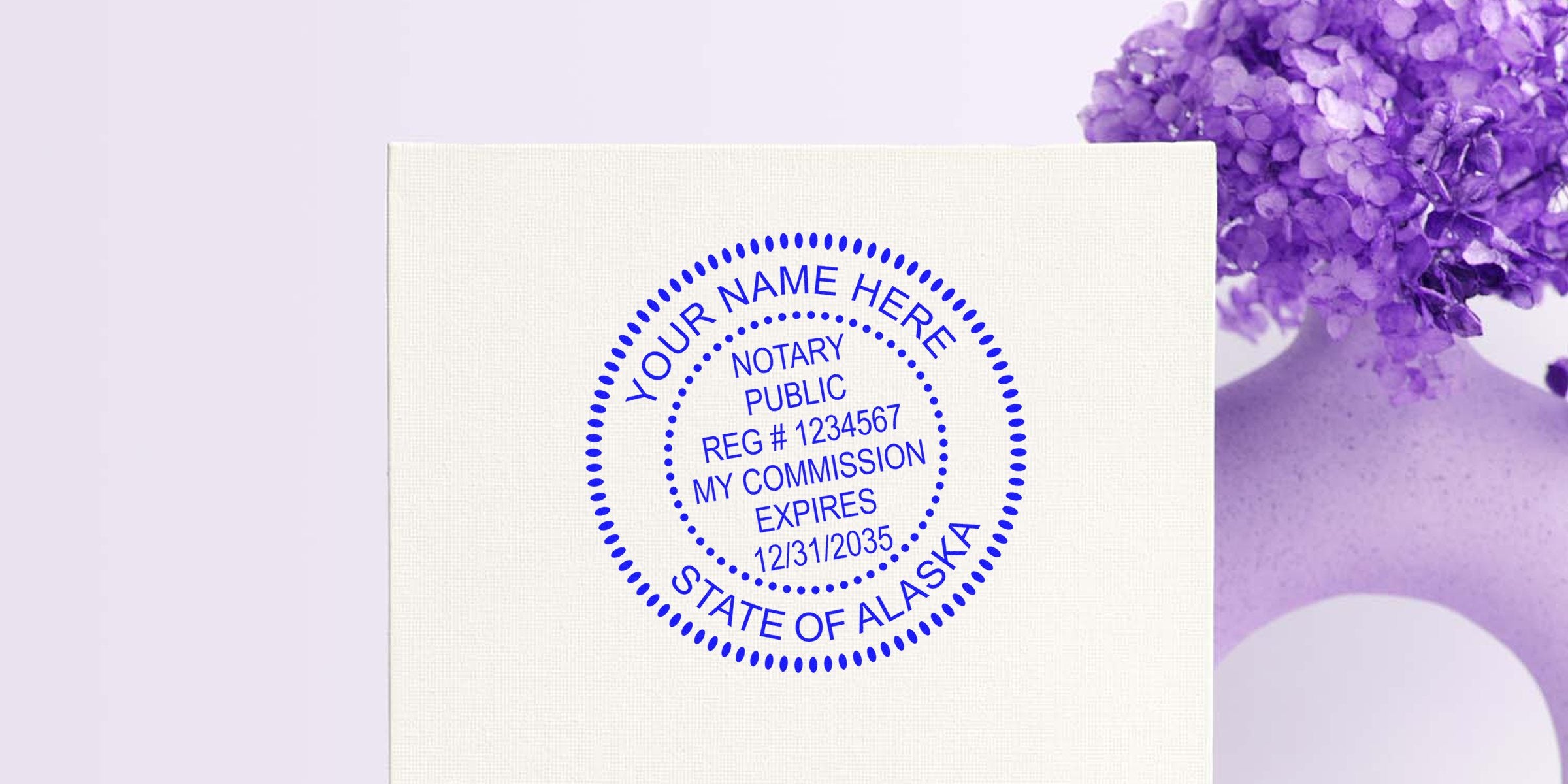 Blue circular notary public seal mockup reading "Your Name Here, State of Alaska" on textured white card next to purple hydrangea bouquet in vase, customizable stamp design