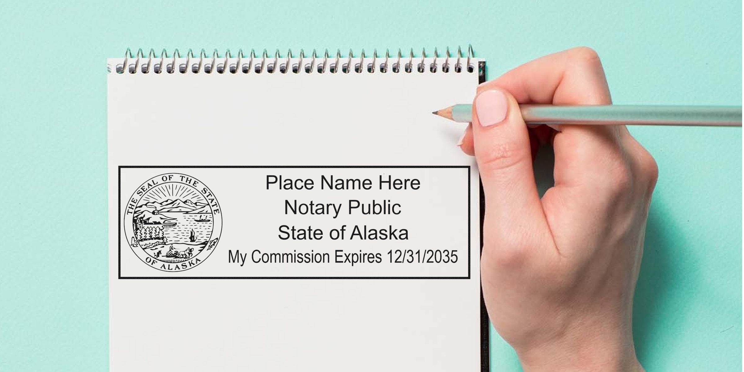 Spiral notebook page showing a State of Alaska notary public stamp template with seal and placeholder text, hand holding a pencil on a teal background