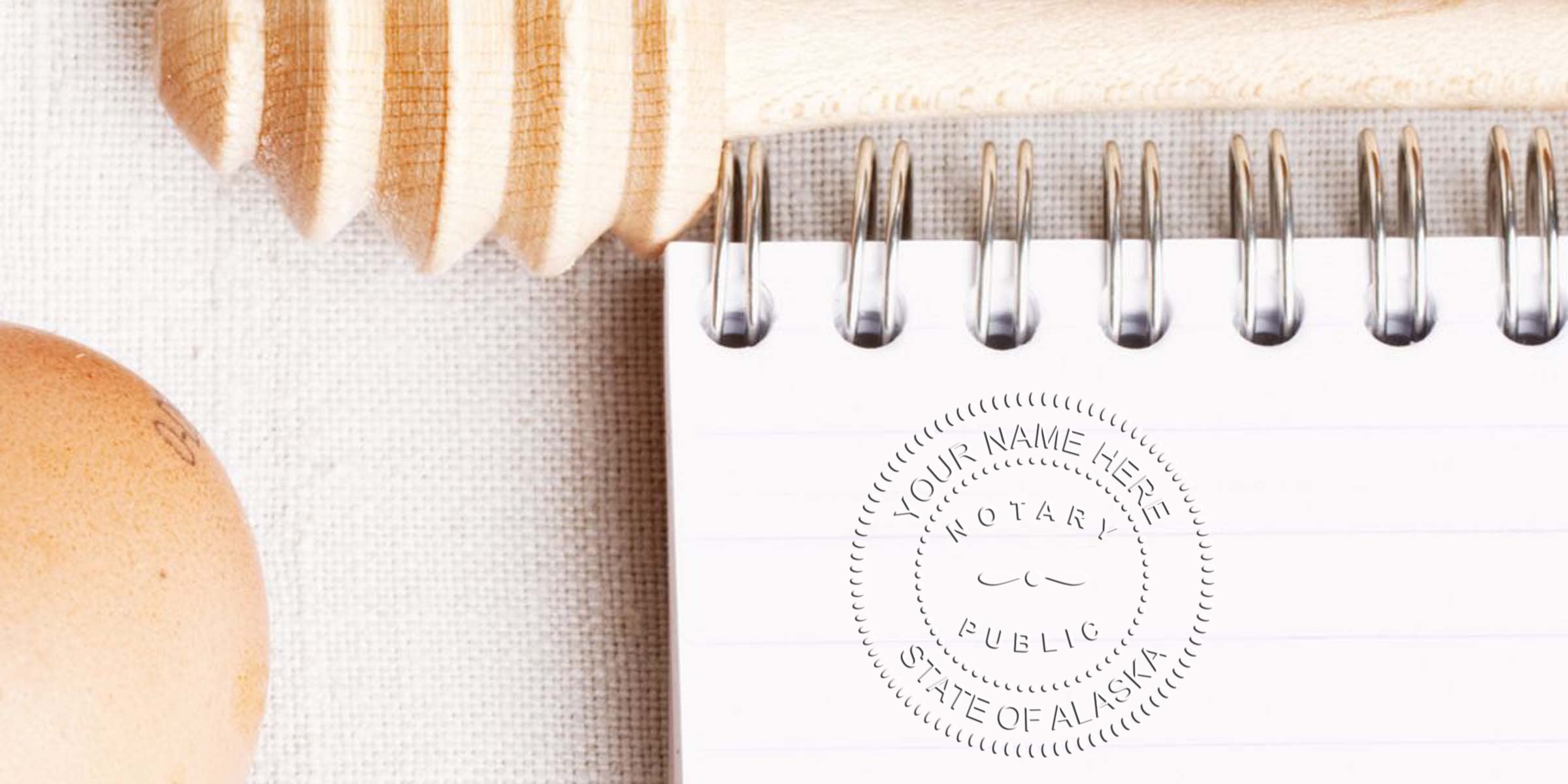 Spiral notepad with faint notary public stamp imprint, wooden honey dipper and brown egg on textured linen background — flatlay showcasing stationery, rustic kitchen props, and official seal for branding or lifestyle content