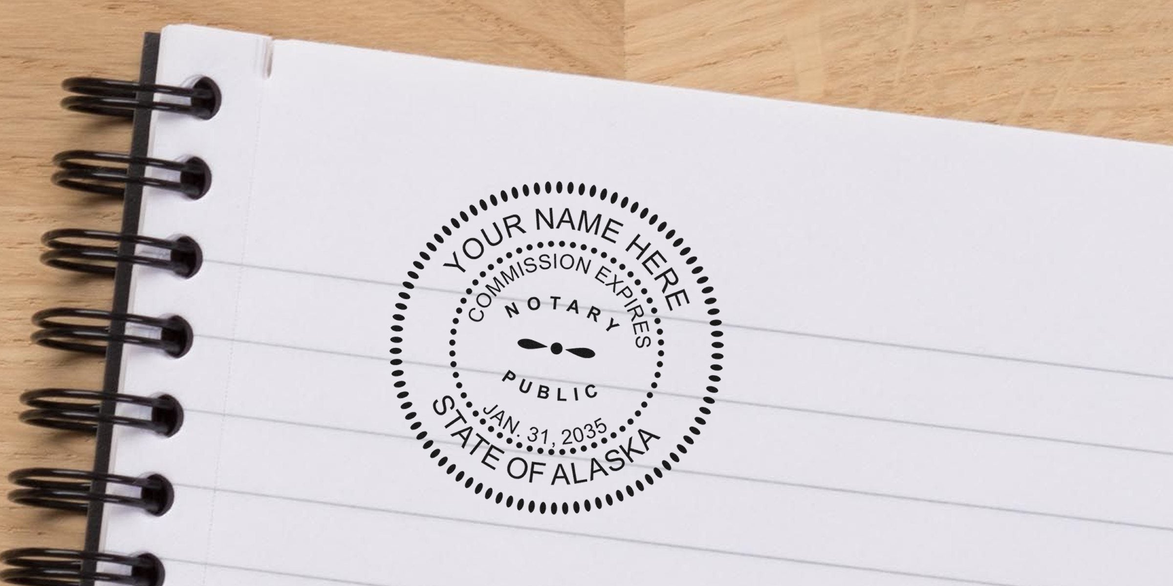 Round black notary seal stamp reading "Your Name Here, Notary Public, State of Alaska" stamped on lined spiral notebook paper
