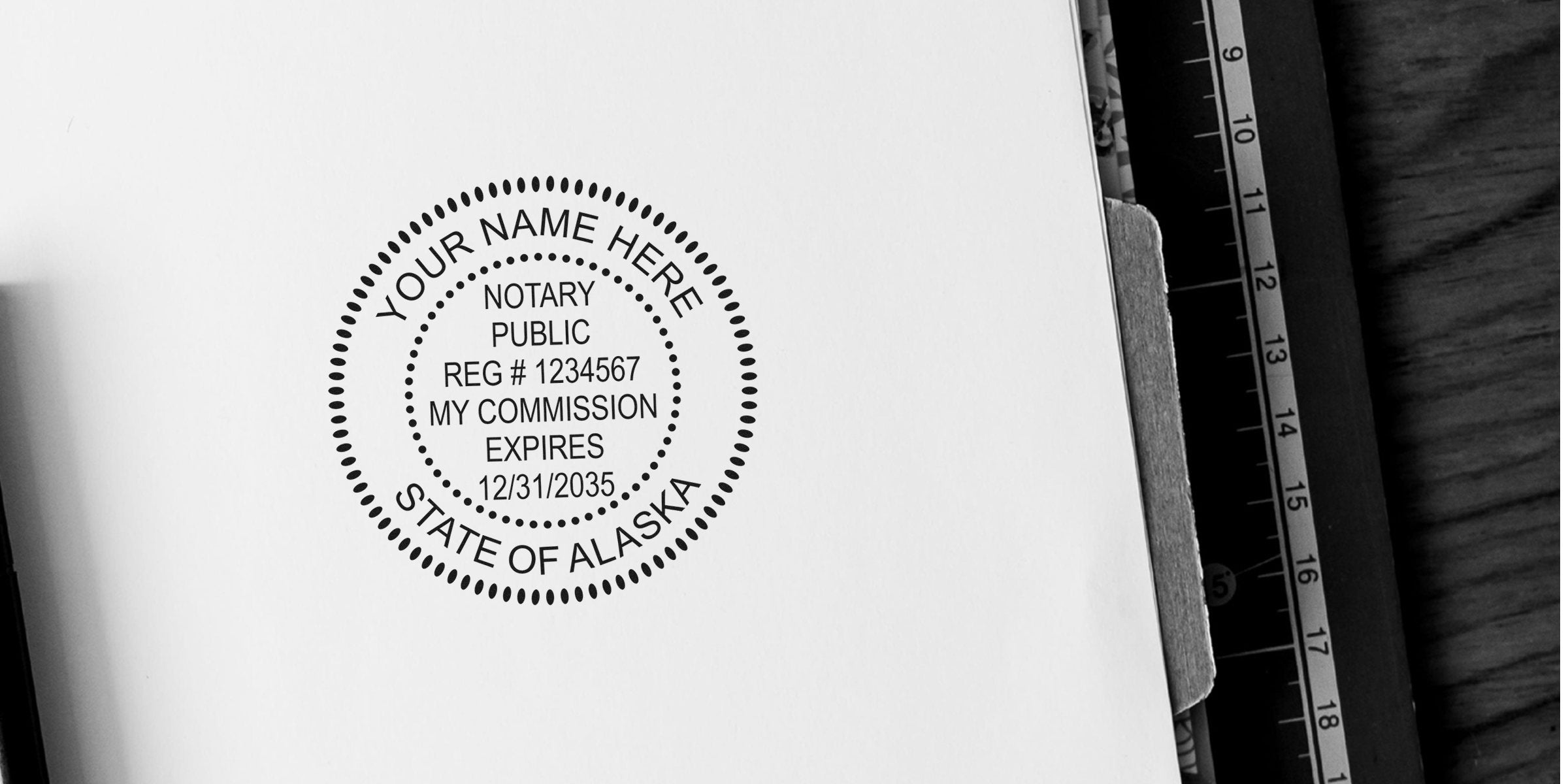 Black circular notary public stamp reading "State of Alaska" with sample registration and commission expiry text on white paper, shown beside a clipboard edge and ruler.