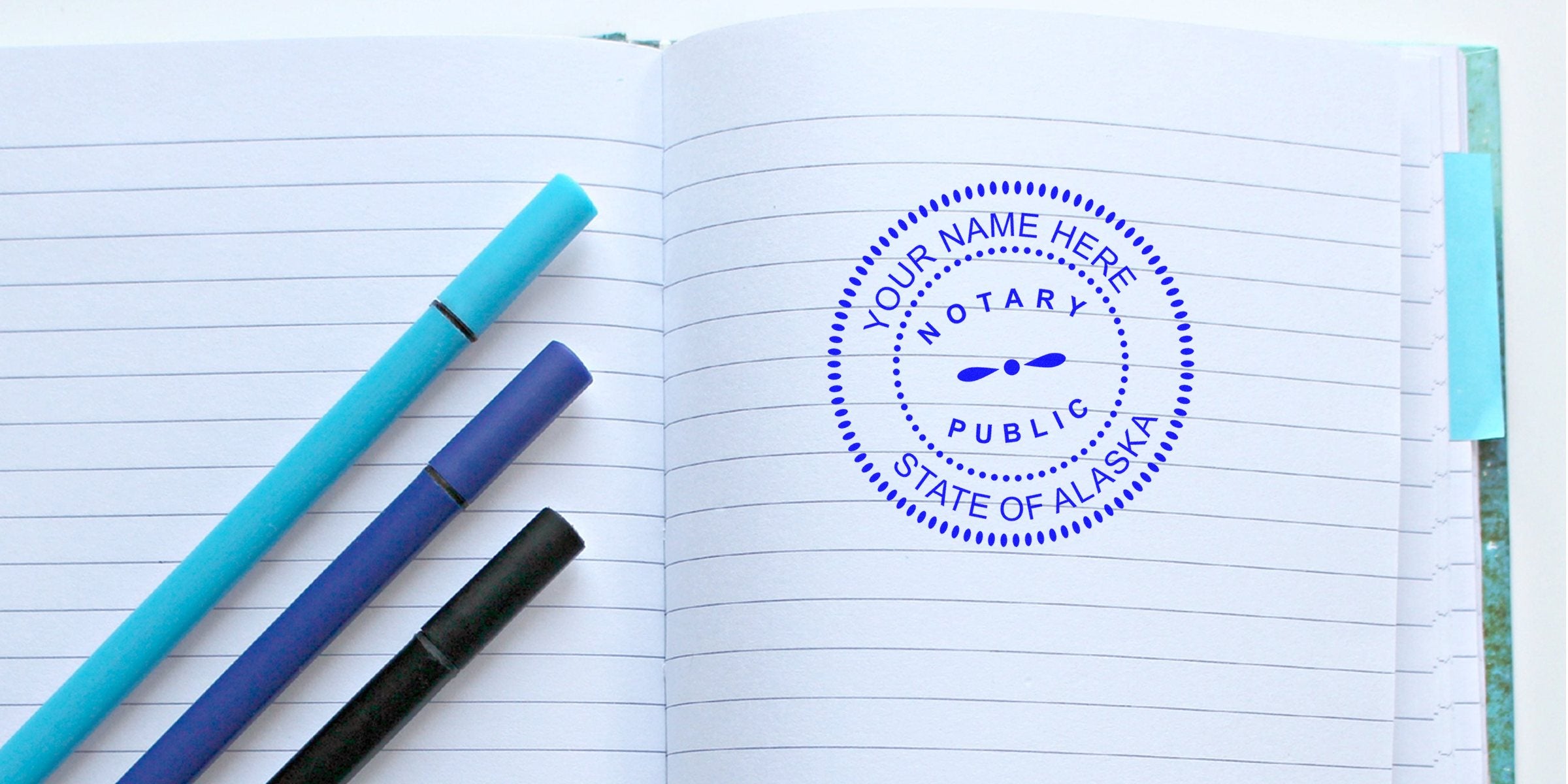Open lined notebook with three blue and black pens and a blue circular "Notary Public, State of Alaska" stamp on the right page, blank lines for notes.