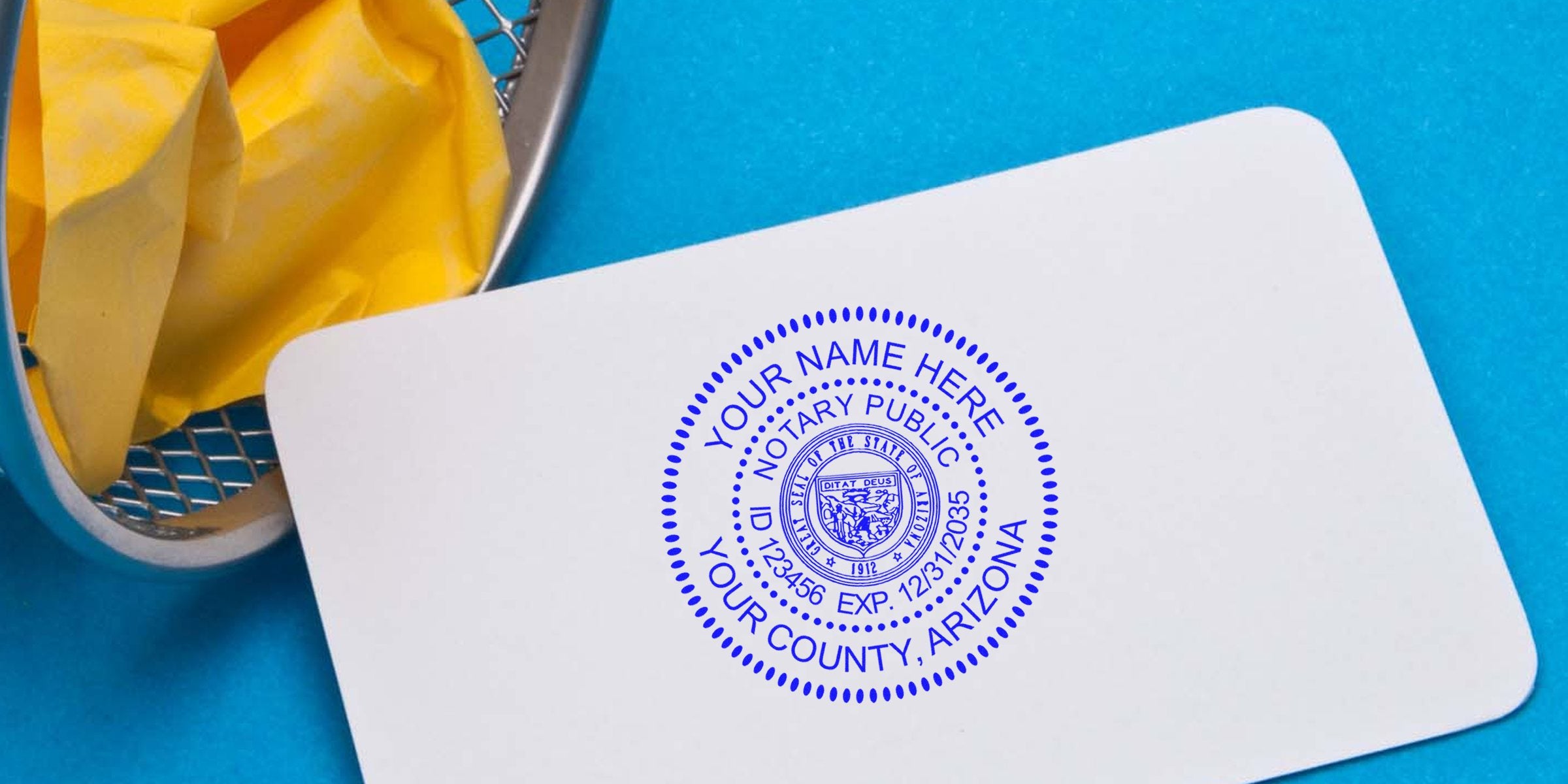 Blue notary public seal reading "Your Name Here, Your County, Arizona" stamped on a white card, on a bright blue background with a metal wastebasket holding crumpled yellow paper.