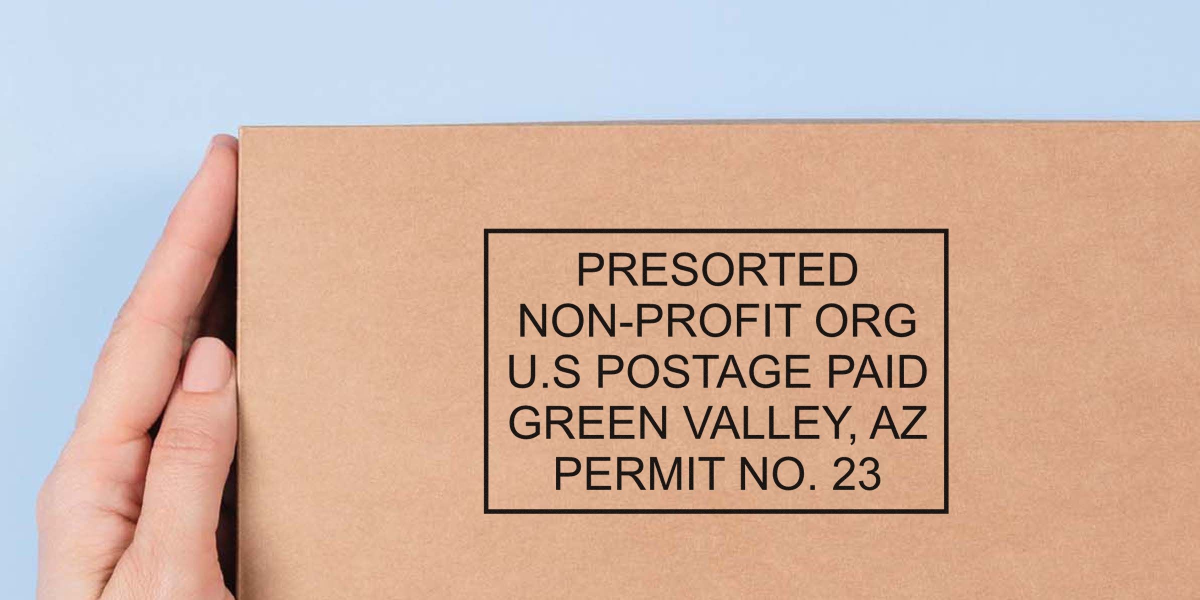 Cardboard box being held, with a postage-style label that reads “PRESORTED NON-PROFIT ORG U.S. POSTAGE PAID GREEN VALLEY, AZ PERMIT NO. 23.”