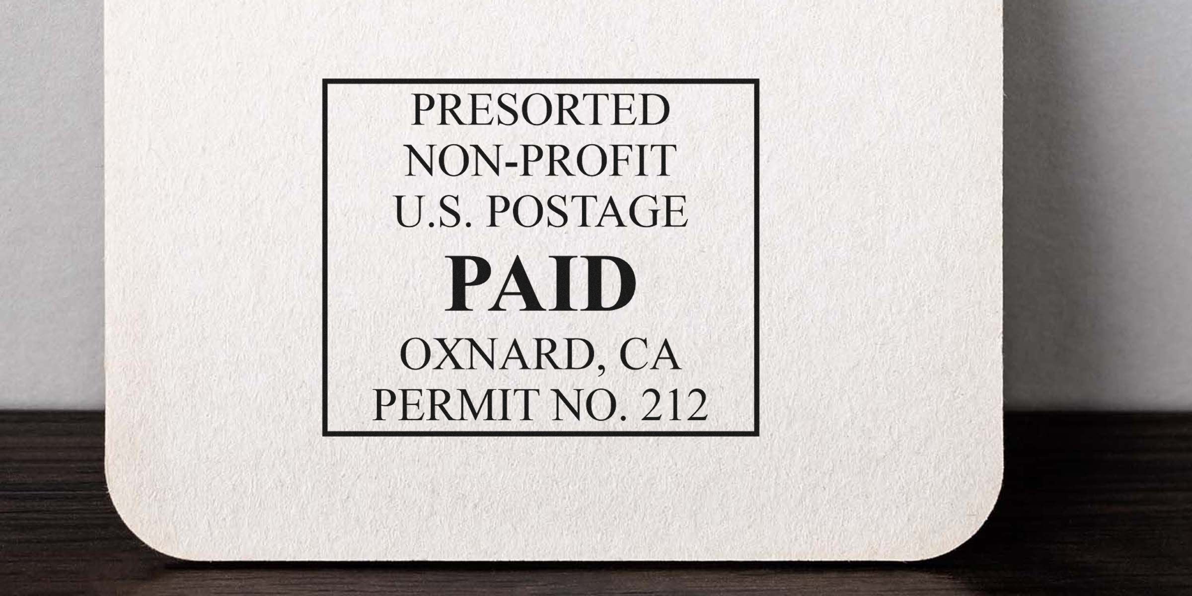 A postage card with a bold “PAID” stamp inside a black square, showing Oxnard, CA and Permit No. 212.