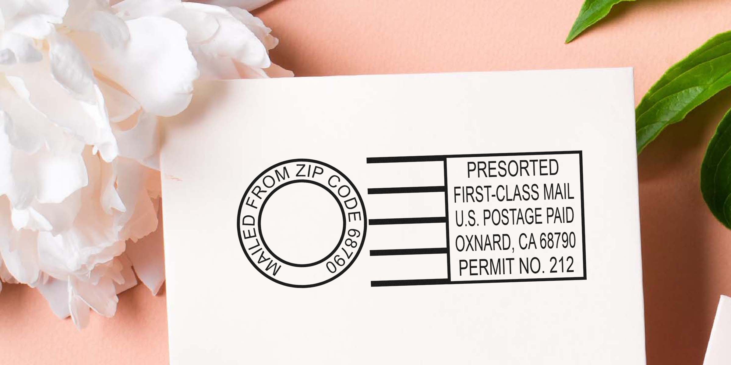 Close-up of a white envelope featuring a circular stamp and a boxed “PRESORTED FIRST-CLASS MAIL U.S. POSTAGE PAID” label, with pink background and a few white flowers nearby.