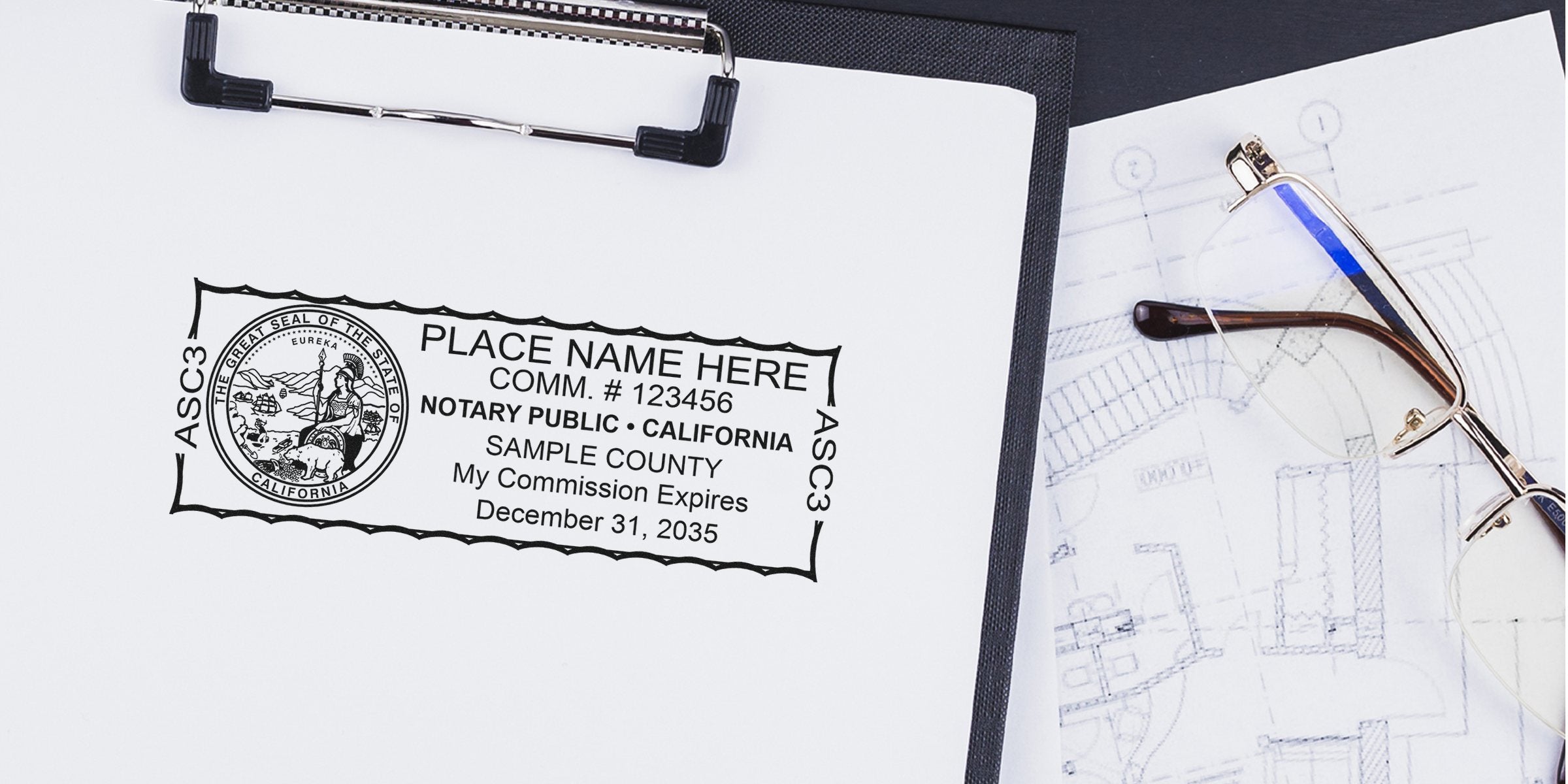 California notary public stamp on clipboard showing sample commission details, placed next to eyeglasses and architectural blueprints