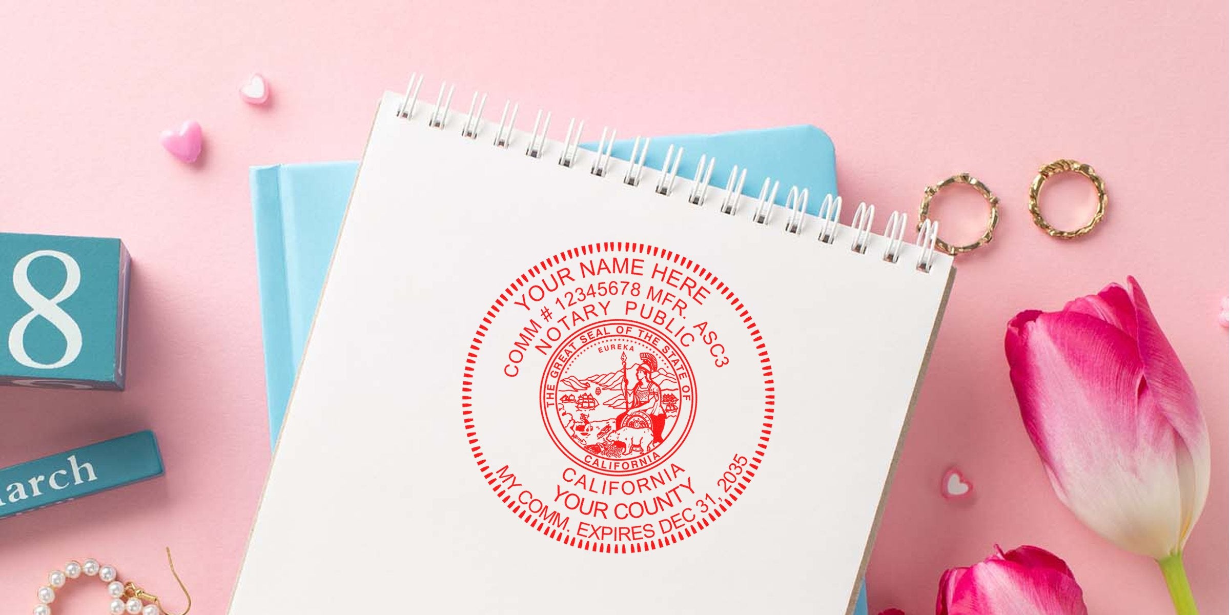 Spiral notebook page stamped with a red California notary public seal, on pink desk with blue March calendar block showing "8", pink tulips, gold rings and small heart embellishments.