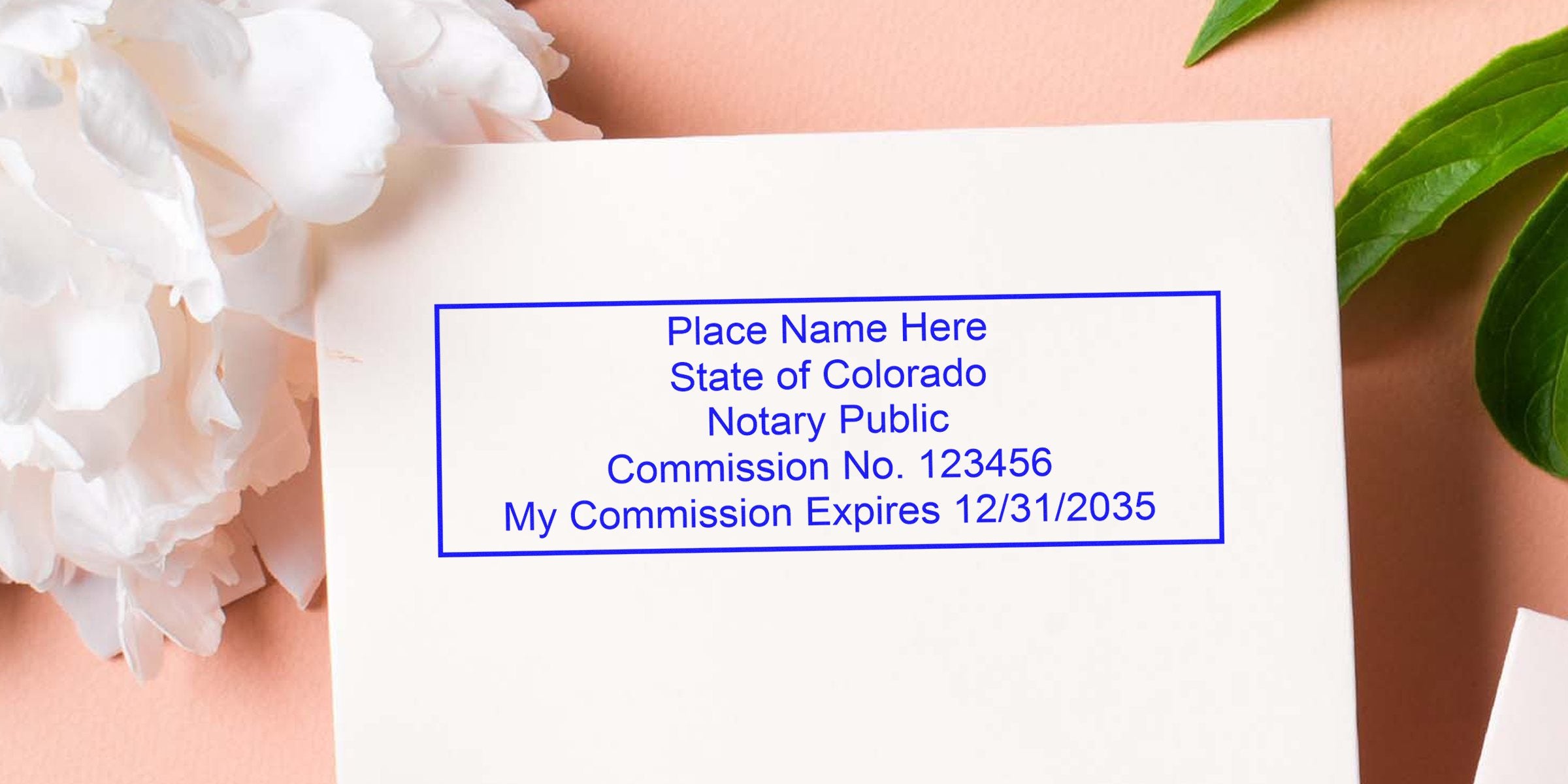 Blue rectangular Colorado notary stamp template on white card with placeholder name, commission no. 123456 and commission expires 12/31/2035, styled with white peony and green leaves on a peach background