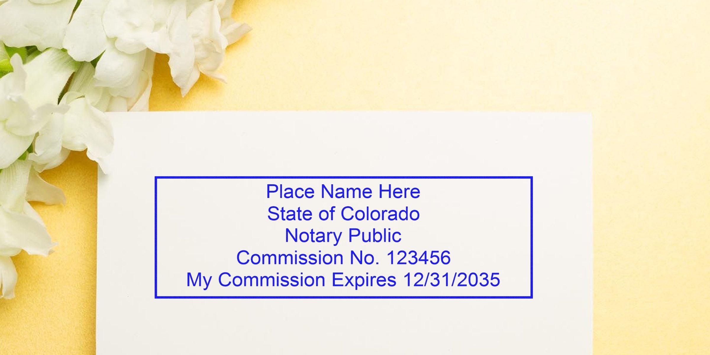 Blank Colorado notary stamp mockup in blue on white paper with placeholder name, commission number and expiration date, set on a yellow background with white flowers