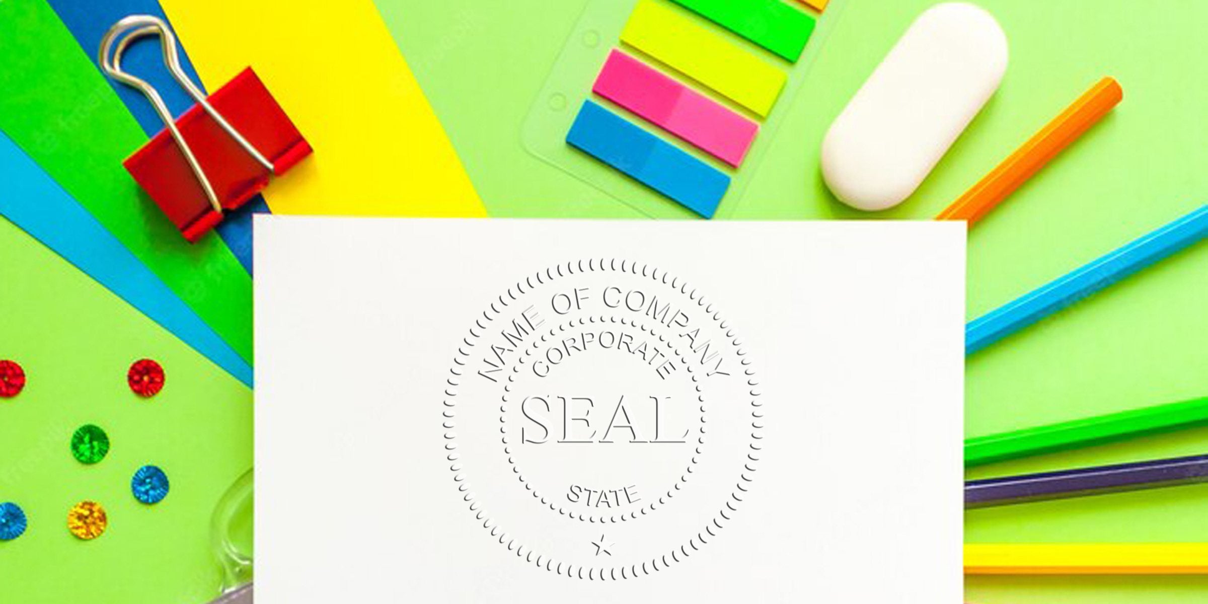 Colorful desk setup with a white card featuring an embossed circular seal that reads SEAL, surrounded by bright stationery.
