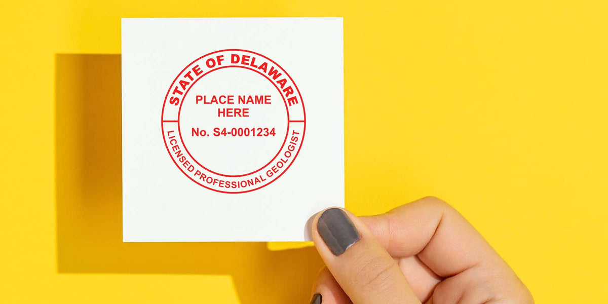 Hand holding a Delaware geologist seal against a yellow background.