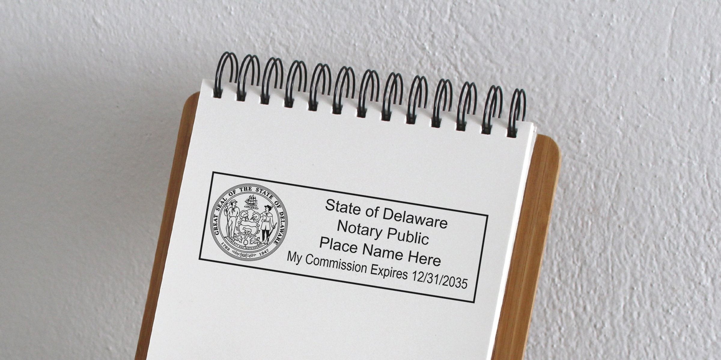 Spiral-bound notepad page showing a rectangular State of Delaware notary public stamp with state seal, placeholder name text and commission expiration date 12/31/2035 on textured white wall background
