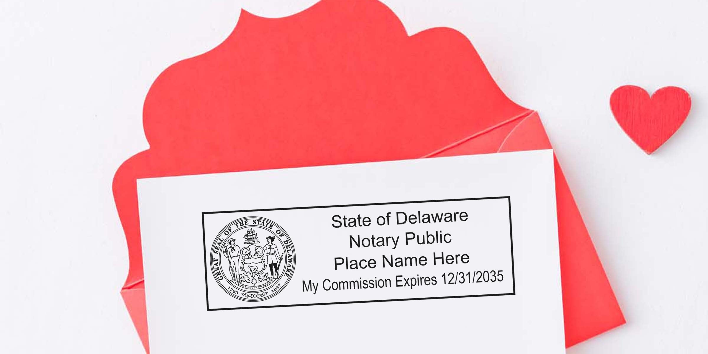 Red envelope with white card showing a Delaware notary public stamp and placeholder name, small red wooden heart beside it, flat lay background