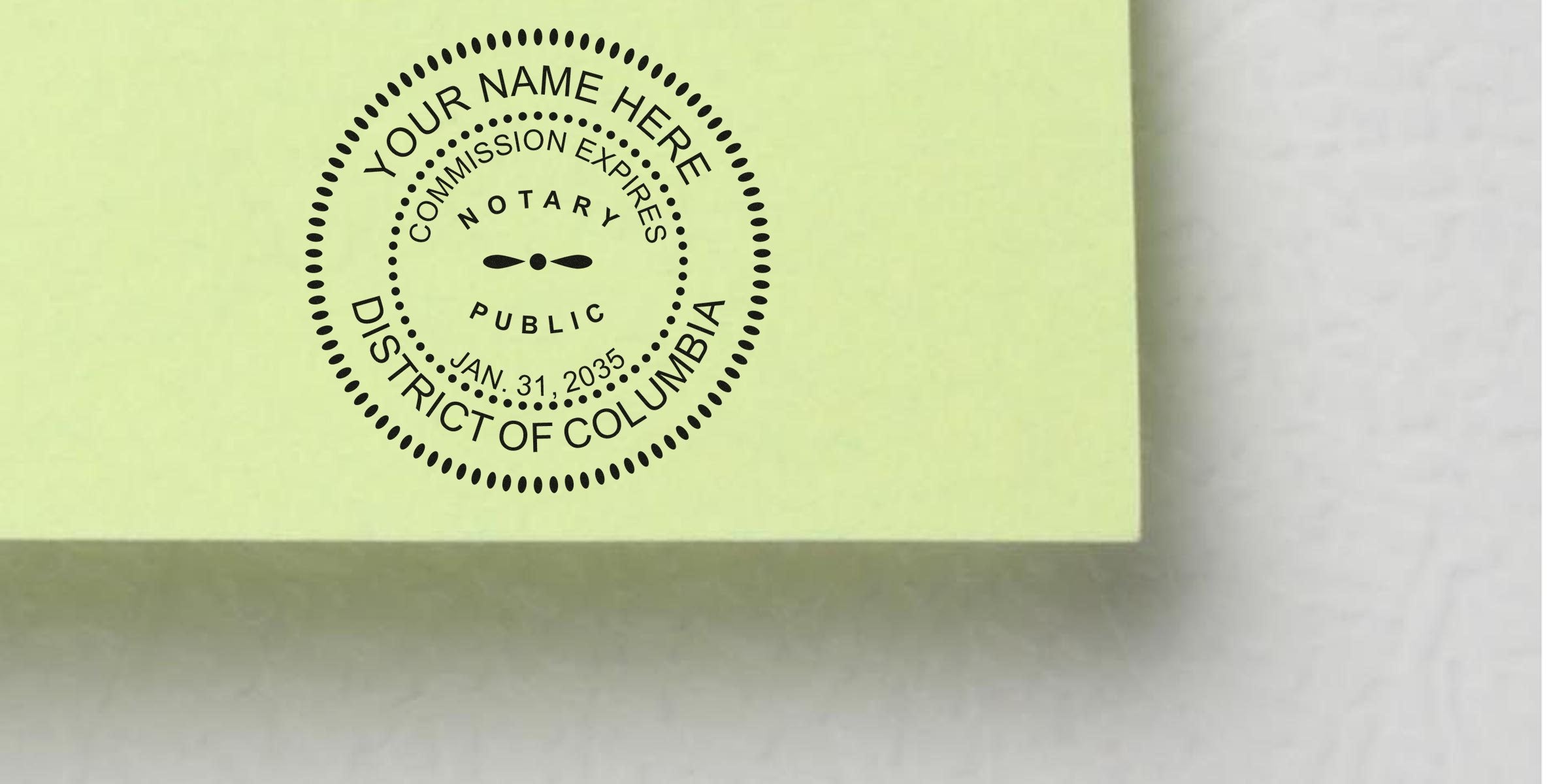 Circular black notary public stamp mockup on pale yellow paper reading "Your Name Here, Commission Expires Jan. 31, 2035, District of Columbia"