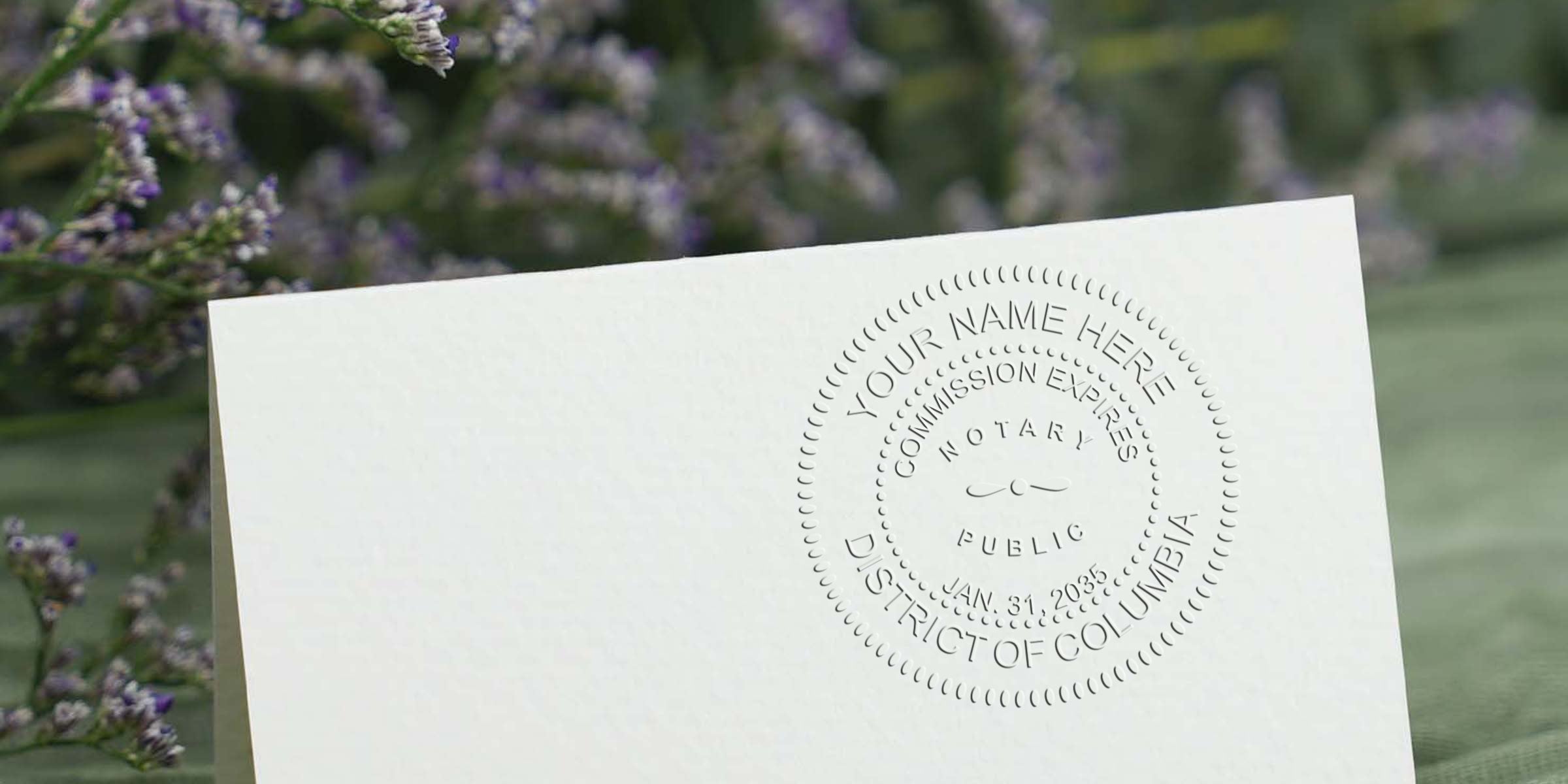 Close-up of an embossed notary public seal on a cream folded card with blurred lavender flowers and green fabric background, stationery detail for notary branding and certification