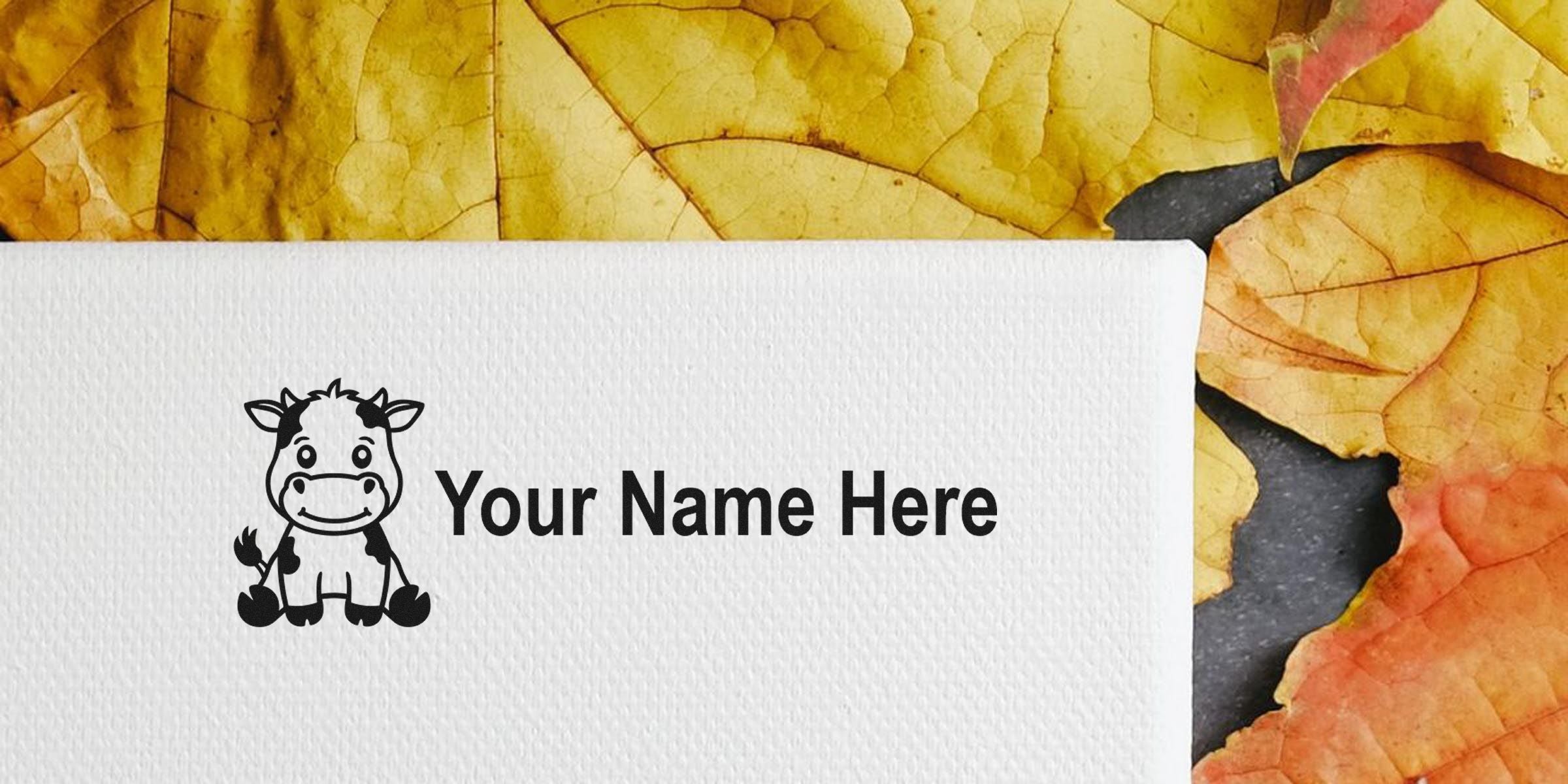 Cartoon cow logo with the text “Your Name Here” on a white textured surface, set against autumn yellow leaves.