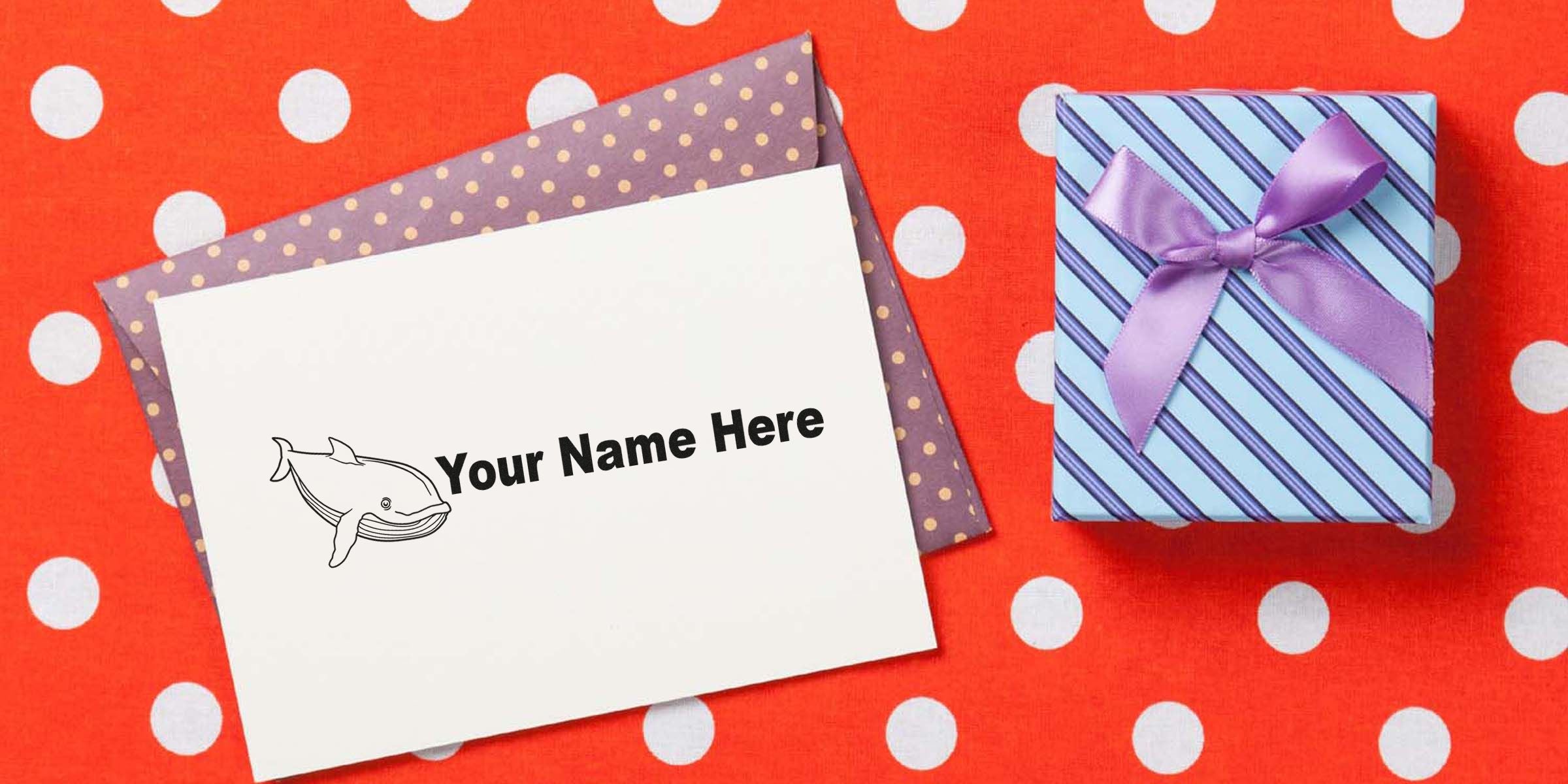 A white card with the text “Your Name Here” and a whale illustration, resting on purple polka-dotted paper beside a striped blue gift box with a purple ribbon on a red polka-dot background.