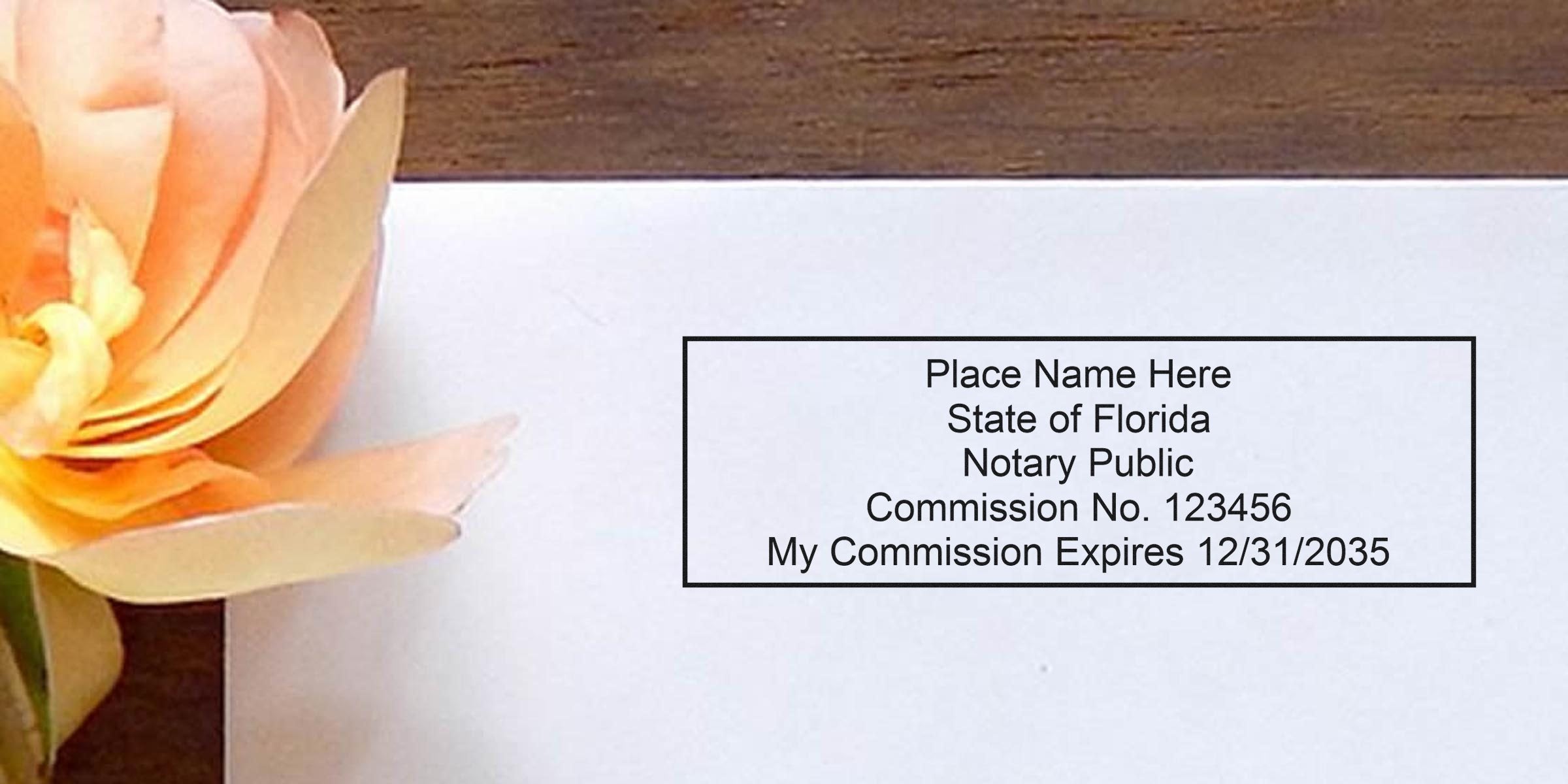 Flat lay of a Florida notary public stamp template on white paper showing placeholder name, commission number and commission expiration date, placed beside a peach paper flower on a wooden desk — notary stamp for legal documents.