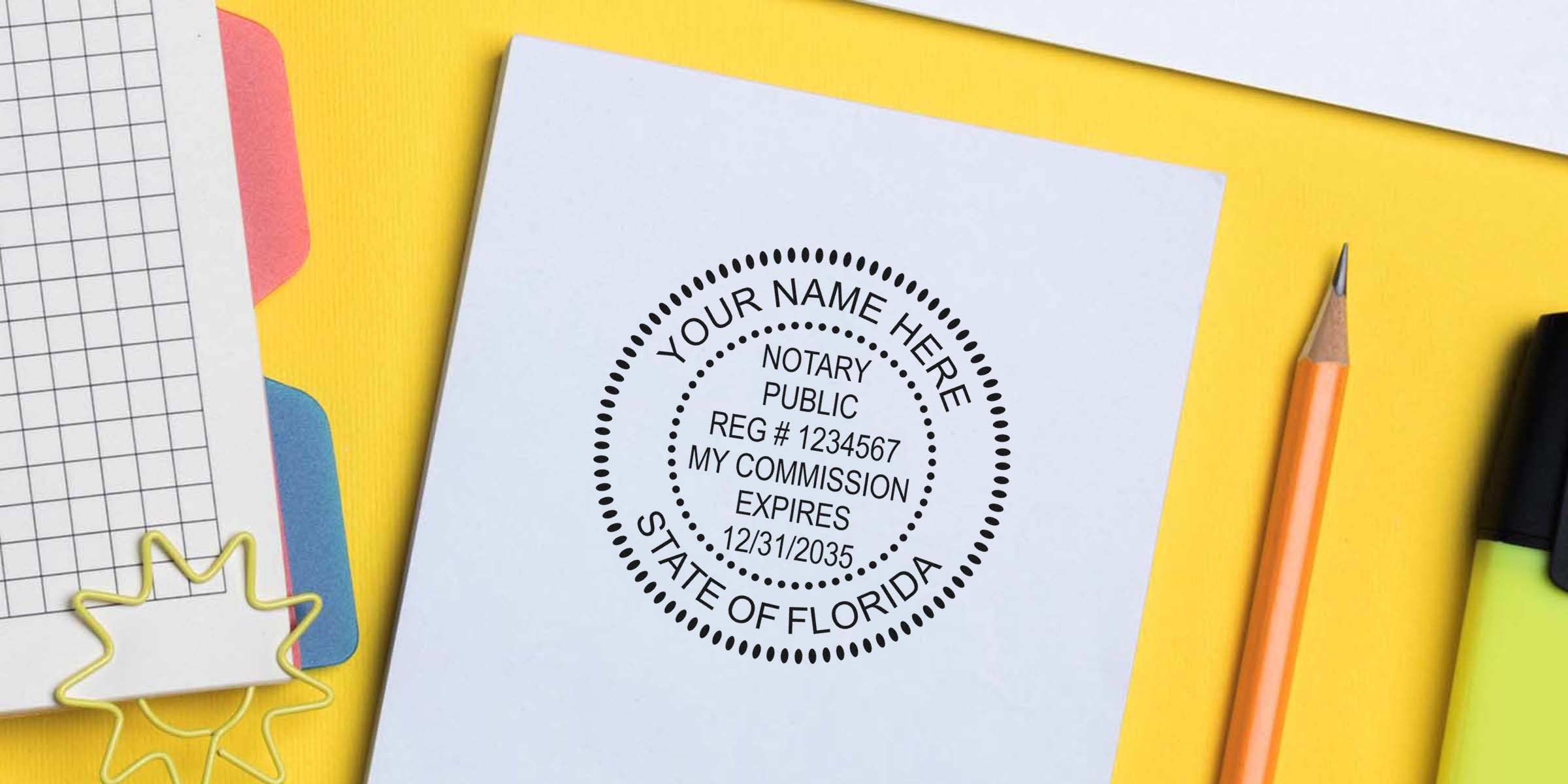 Notary public stamp mockup on white paper reading "Your Name Here, Notary Public, Reg #1234567, My Commission Expires 12/31/2035, State of Florida" on a yellow desk with pencil, highlighter and notebook