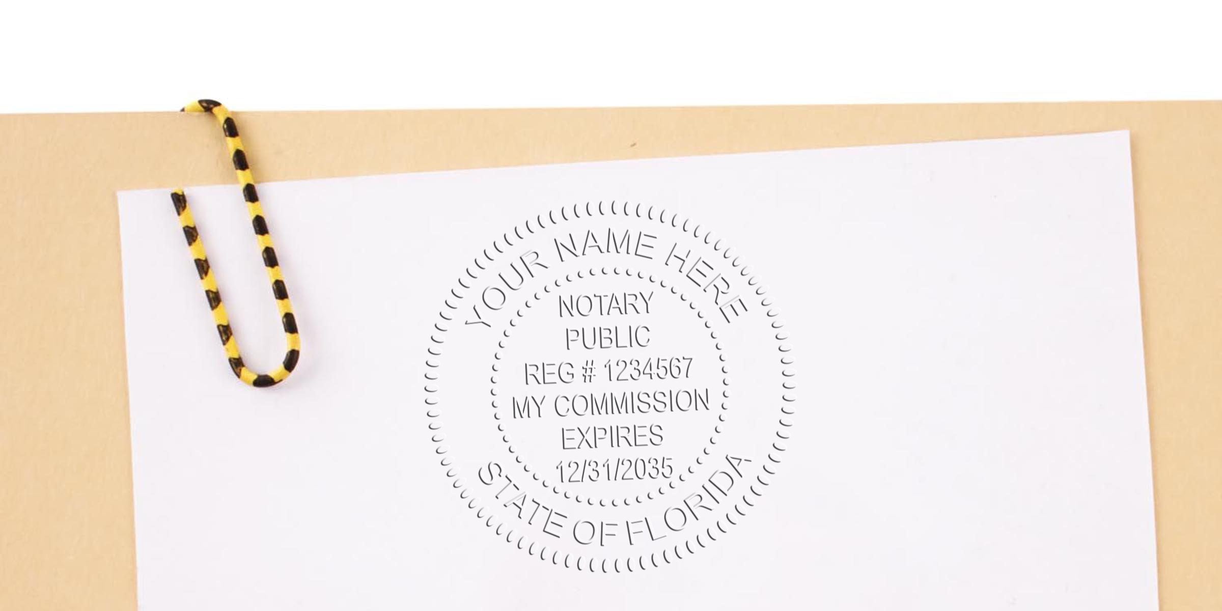 White paper with a circular embossed Florida notary public seal reading "Your Name Here" and commission details, clipped to a beige folder with a yellow-and-black striped paperclip — notary embossing, document verification, legal seal.