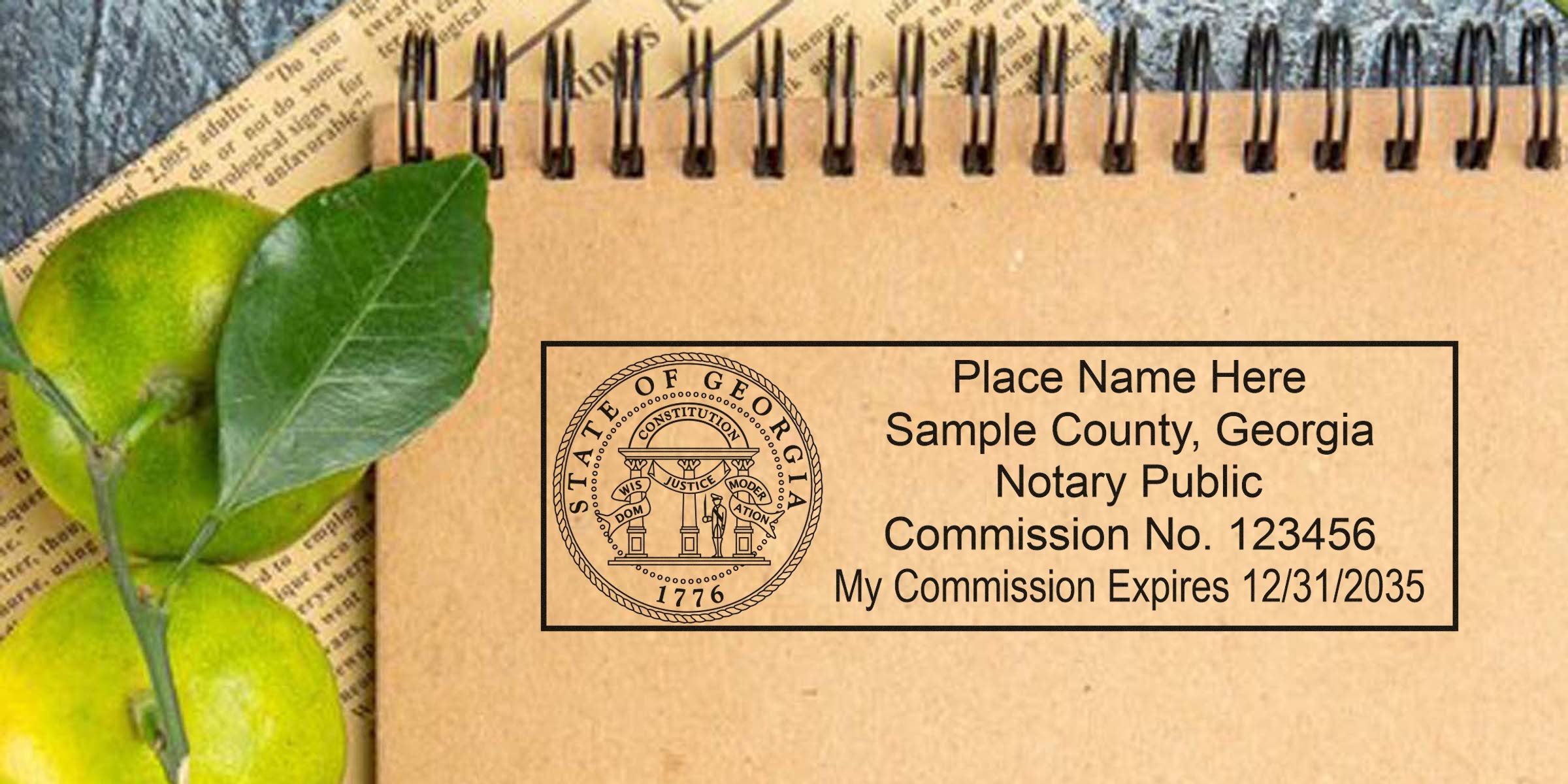 Georgia notary stamp mockup on kraft spiral notebook showing state seal, placeholder name, county, notary public commission number and expiration date beside green limes and leaves