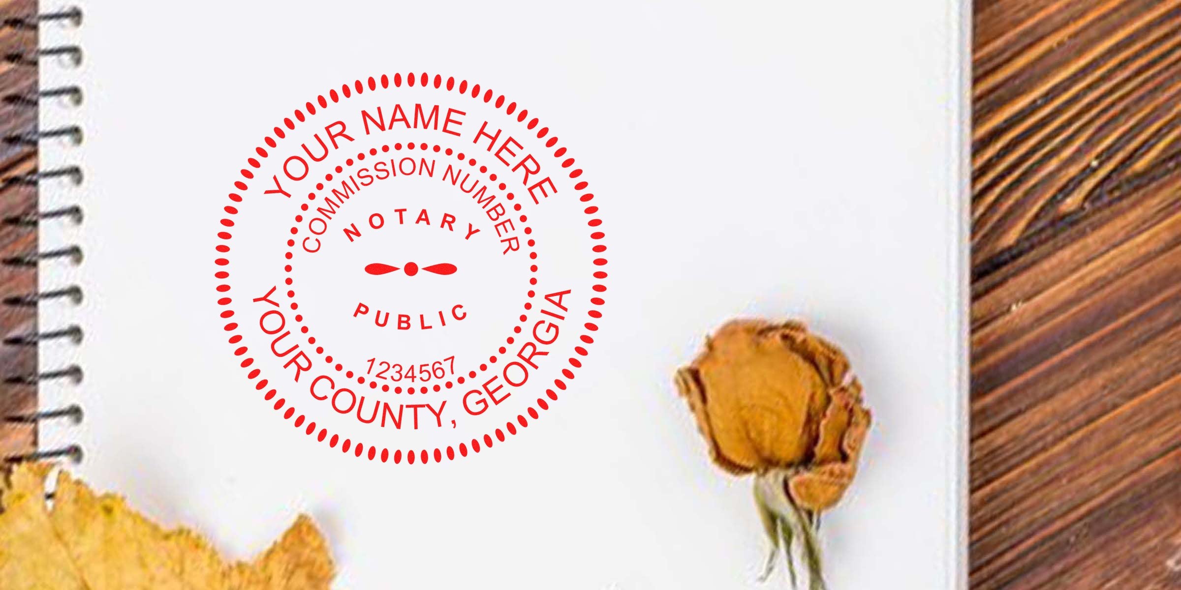 Red circular notary public seal mockup reading "Your Name Here, Your County, Georgia" on spiral notebook page with dried rose and wood background