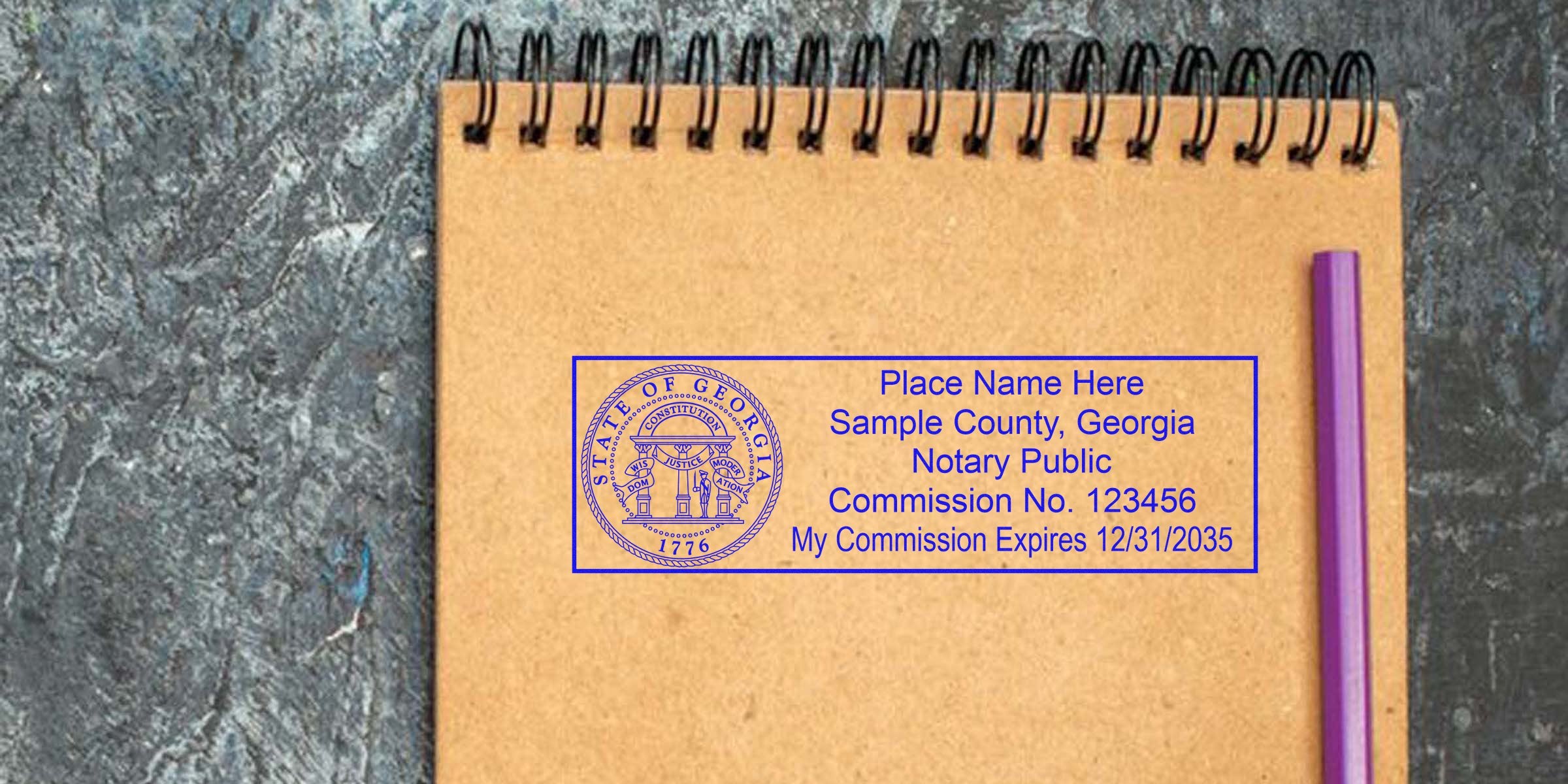Sample blue Georgia notary stamp mockup on a brown spiral notebook page with commission details, placed next to a purple pen on a dark textured background — notary stamp template for Georgia documents and branding.