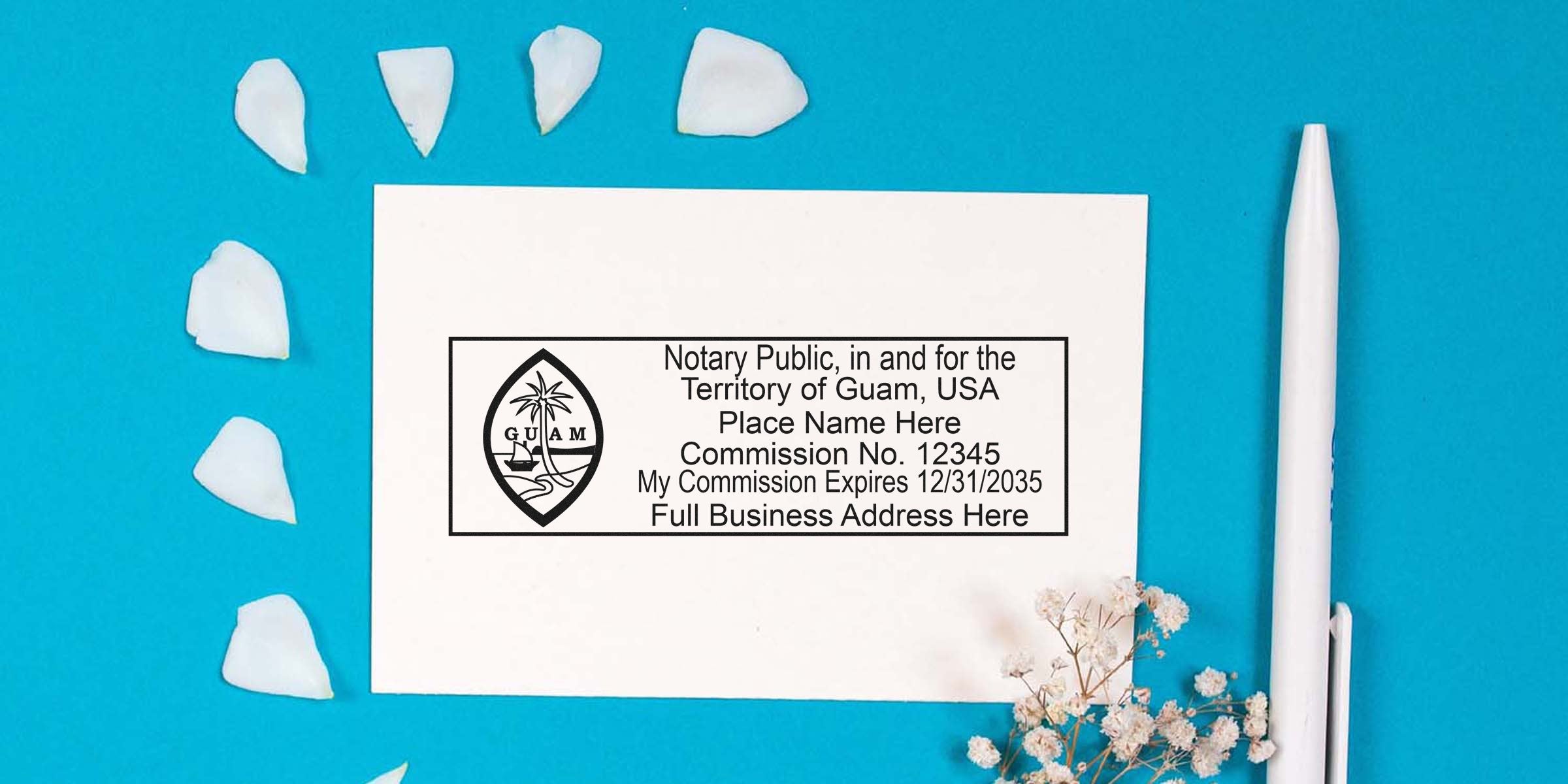 Flat lay of a Guam notary public stamp template on white card with commission details, surrounded by white petals, pen and dried flowers on teal background