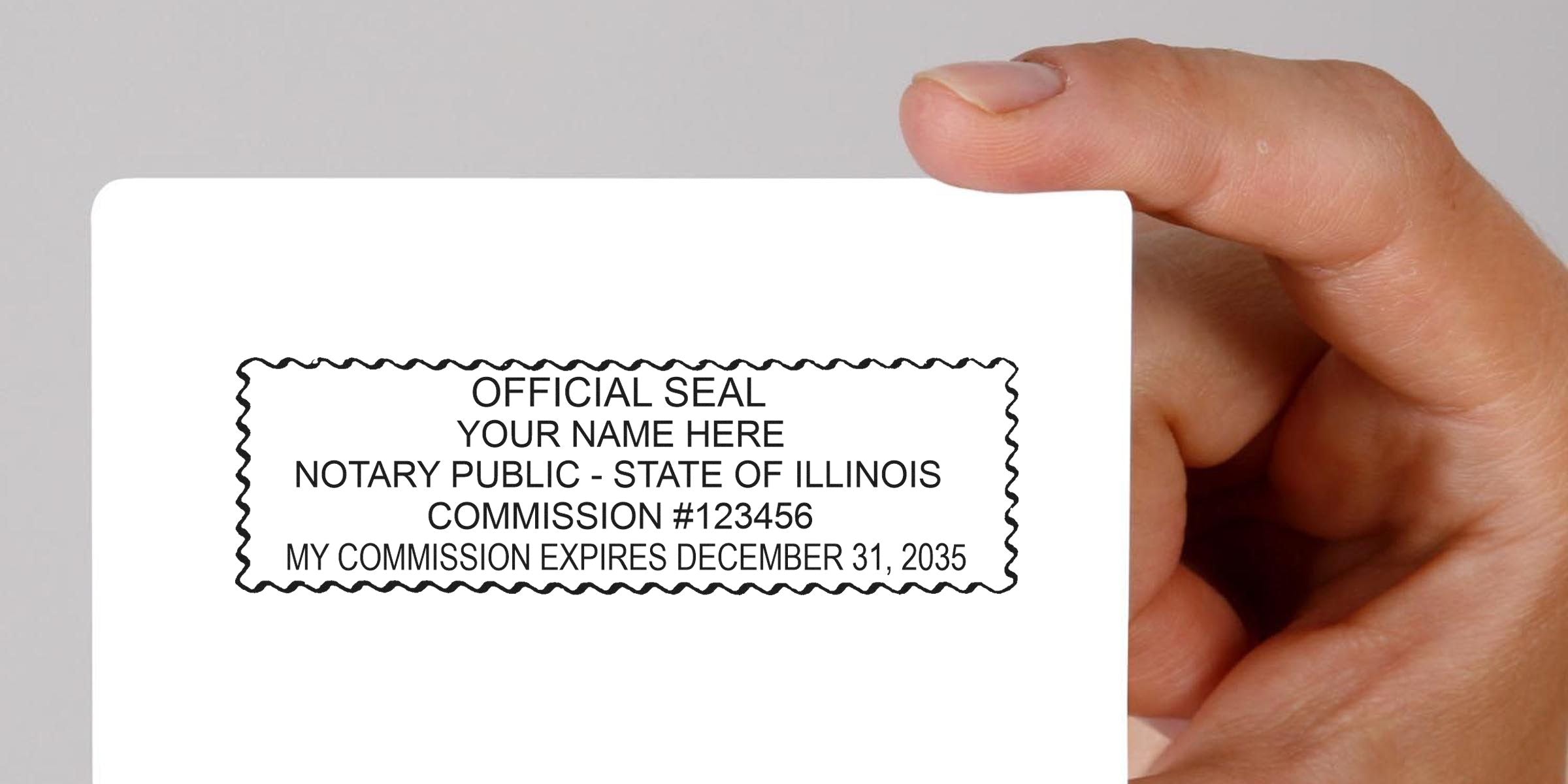 Hand holding white card showing a sample Illinois notary public official seal stamp with commission number and expiration date