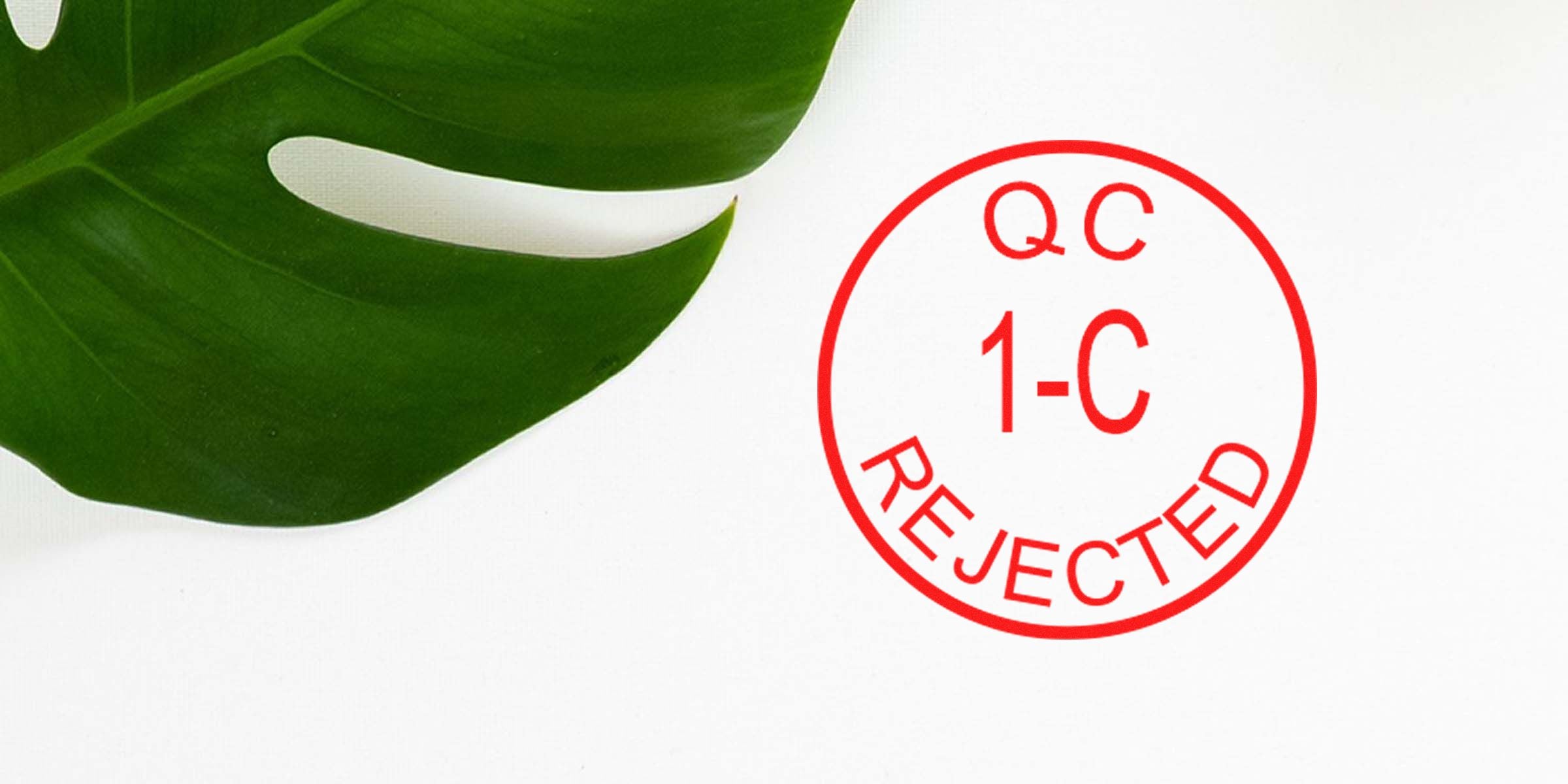 Red circular stamp reading “QC 1-C REJECTED” in red on a white background, with a green leaf partially visible on the left.