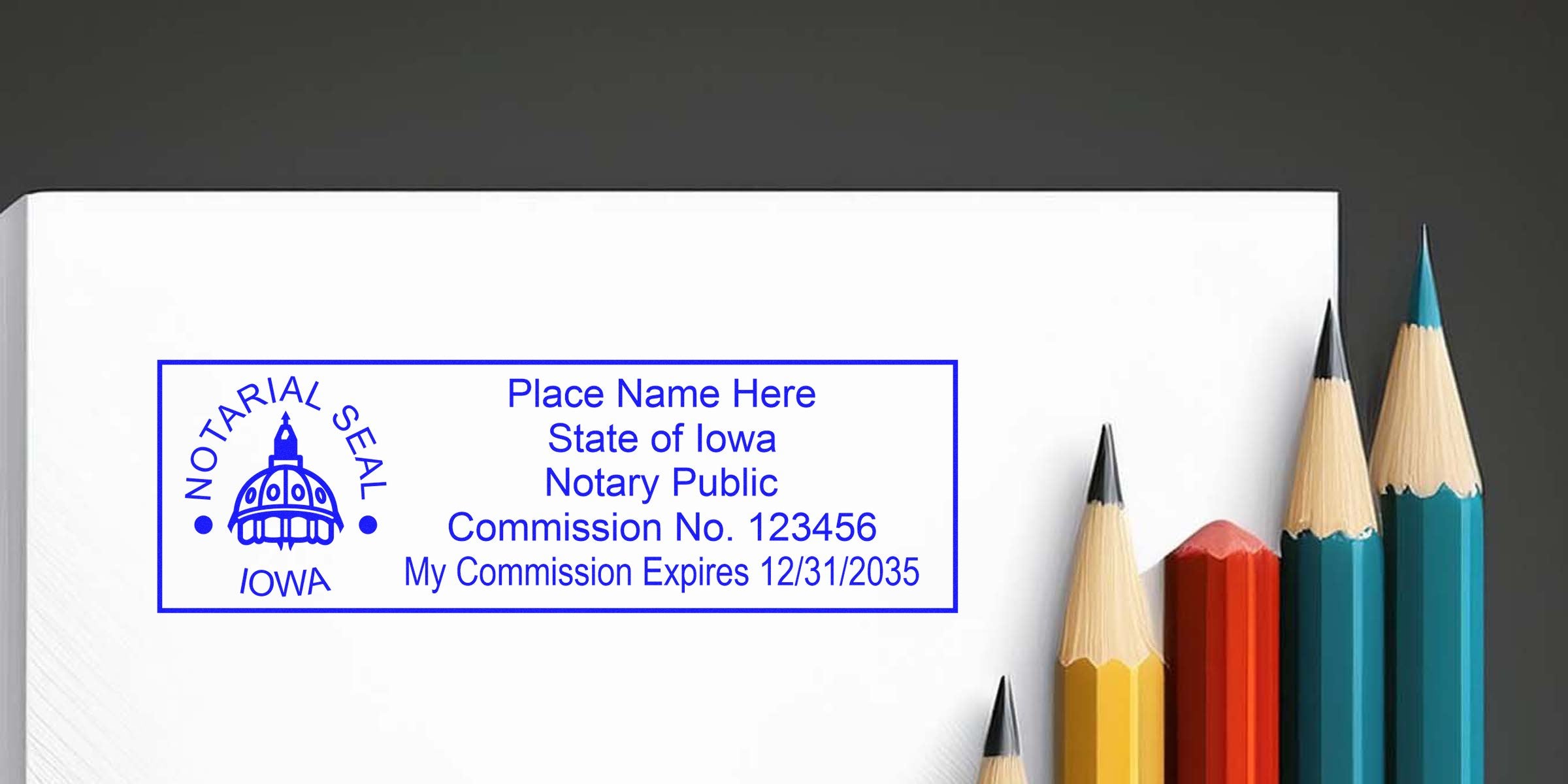 Blue Iowa notarial seal stamp mockup with placeholder notary text and commission details on white paper, beside a row of sharpened colorful pencils (yellow, red, teal) on a dark background