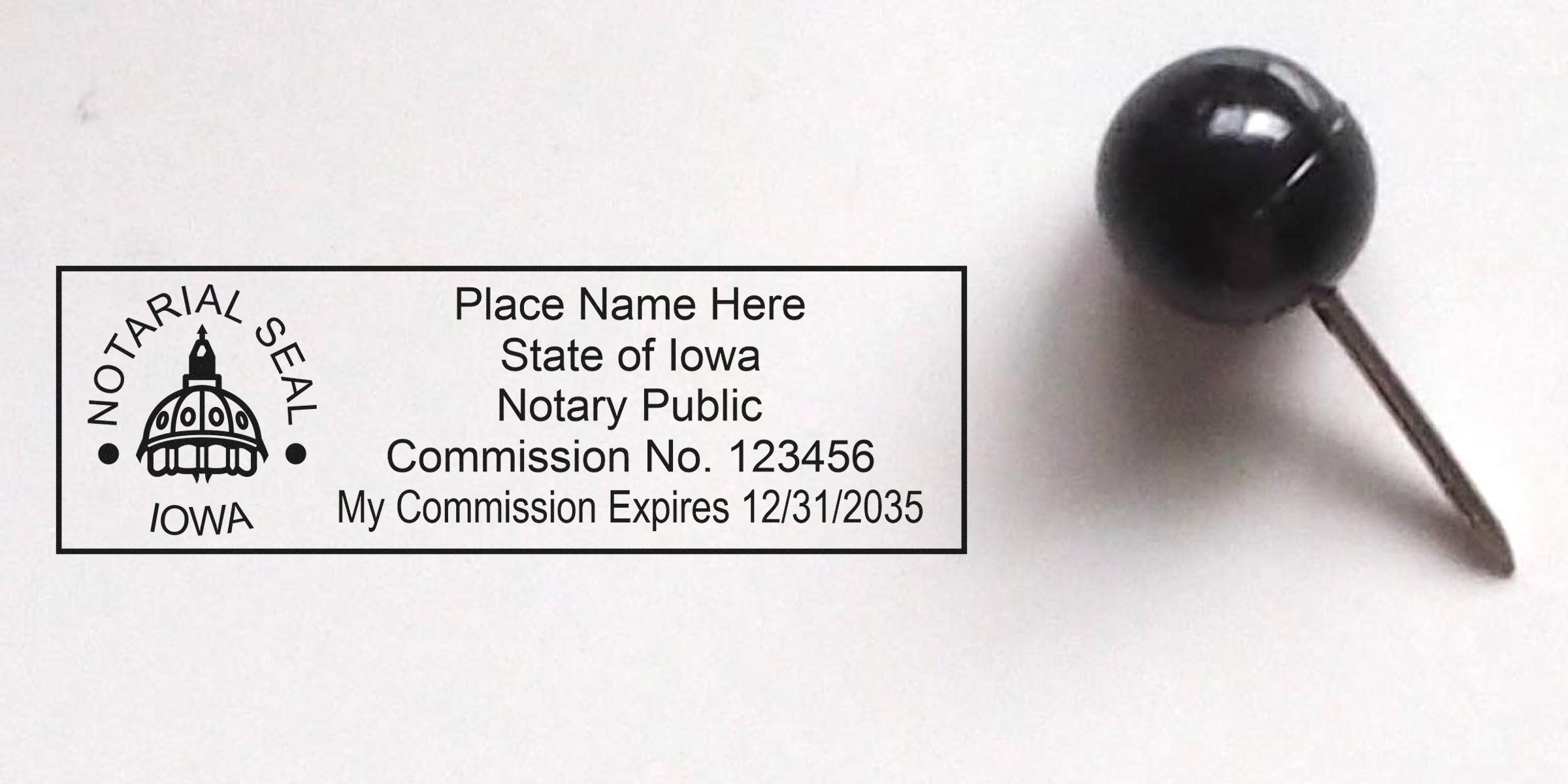 Iowa notary public seal imprint with sample commission number and expiration date displayed inside a rectangular stamp, photographed beside a black map pin on a white background