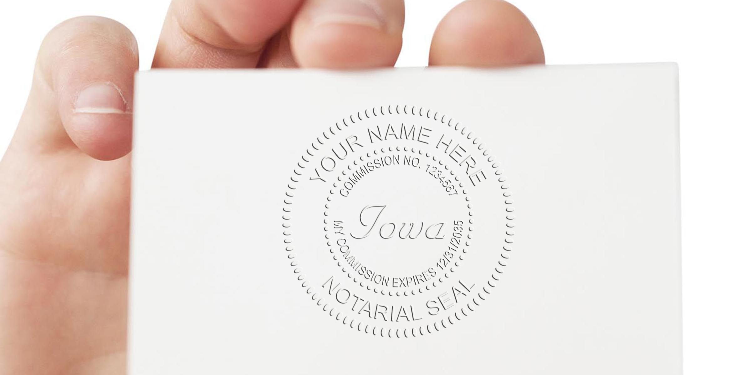 Hand holding white card with embossed circular Iowa notary seal reading "Your Name Here" and "Notarial Seal"
