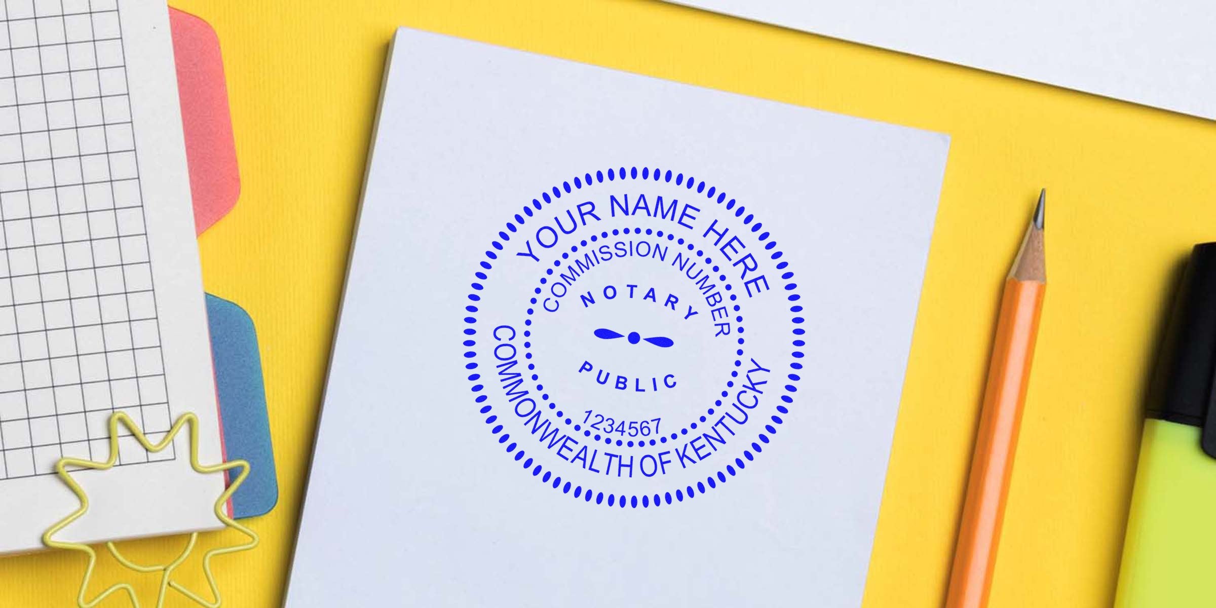 Kentucky notary stamp mockup on white paper: circular blue notary public seal reading "Your Name Here", commission number and "Commonwealth of Kentucky" on yellow desk with pencil and stationery