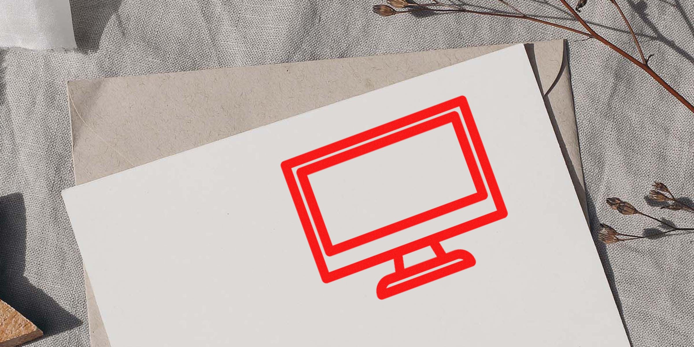 Red outline illustration of a computer monitor on a white card resting on a grey fabric surface.
