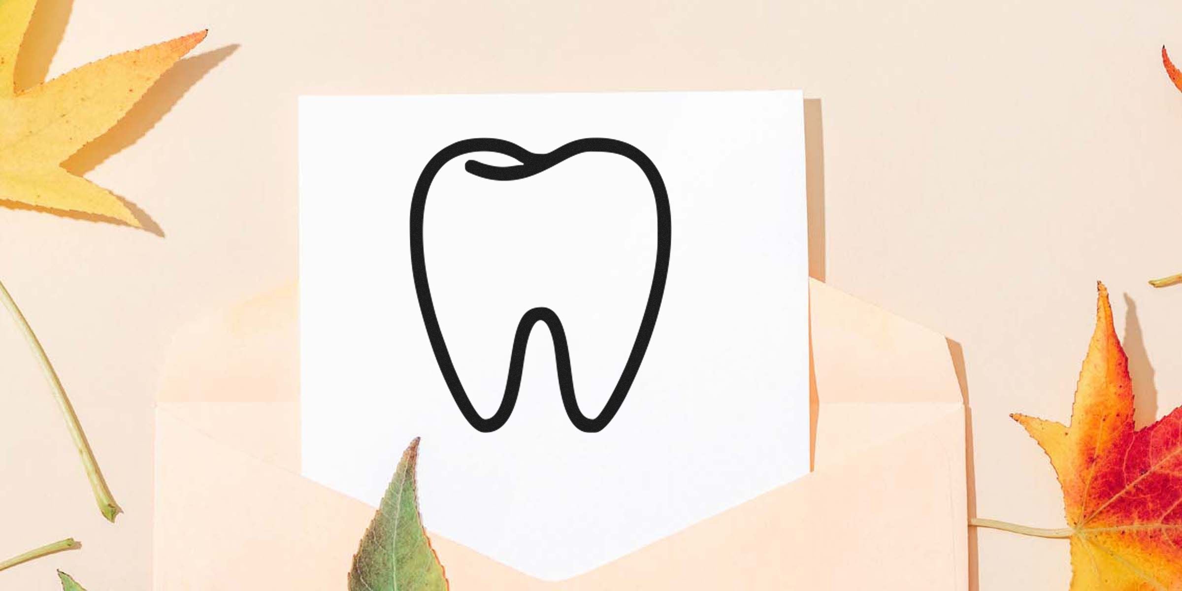 A simple black line drawing of a tooth on a white card, surrounded by fall leaves.