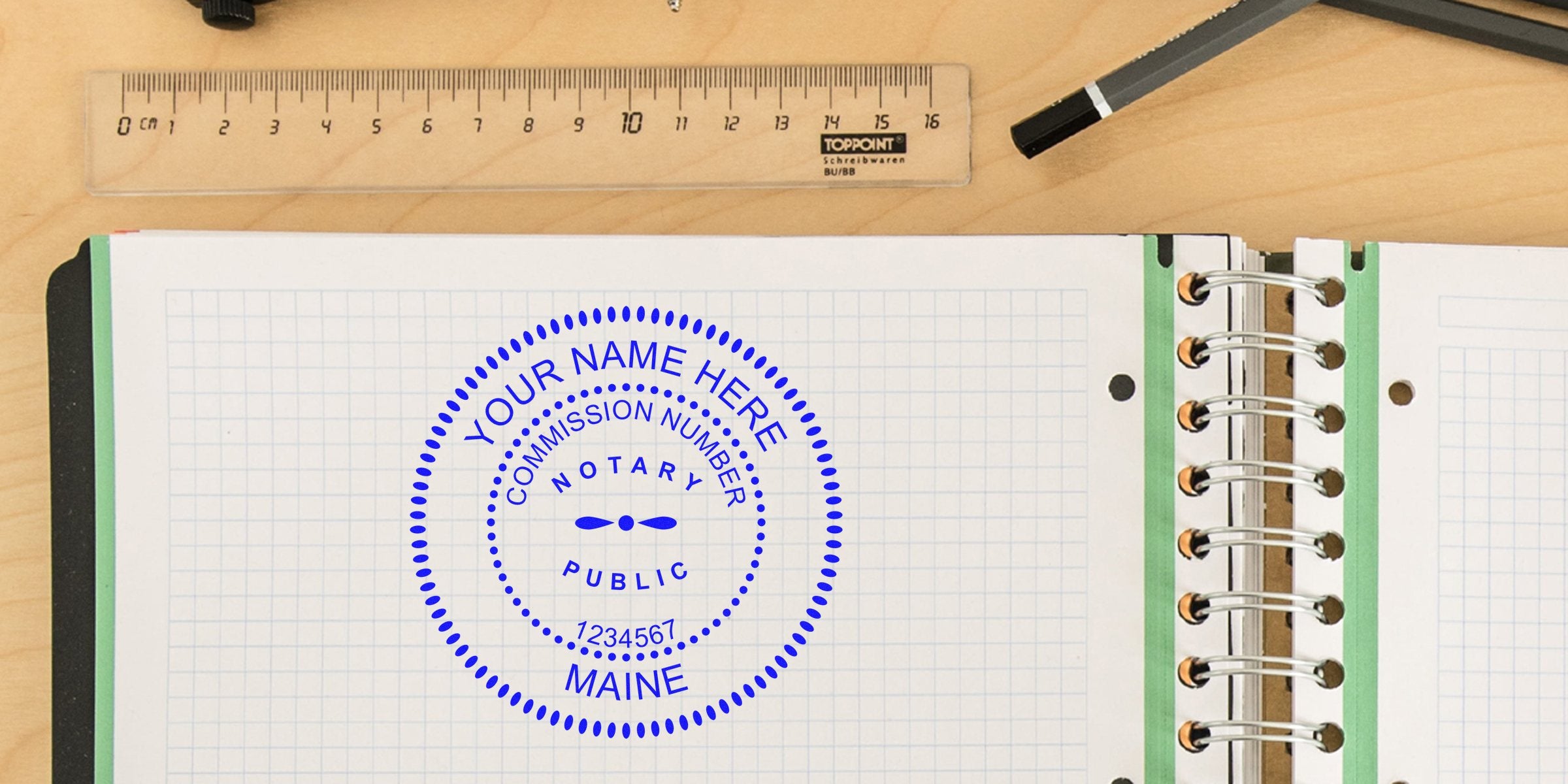 Blue circular Maine notary public stamp mockup with customizable name and commission number on graph-paper notebook page, shown alongside a clear ruler and pencil on a light wooden desk.