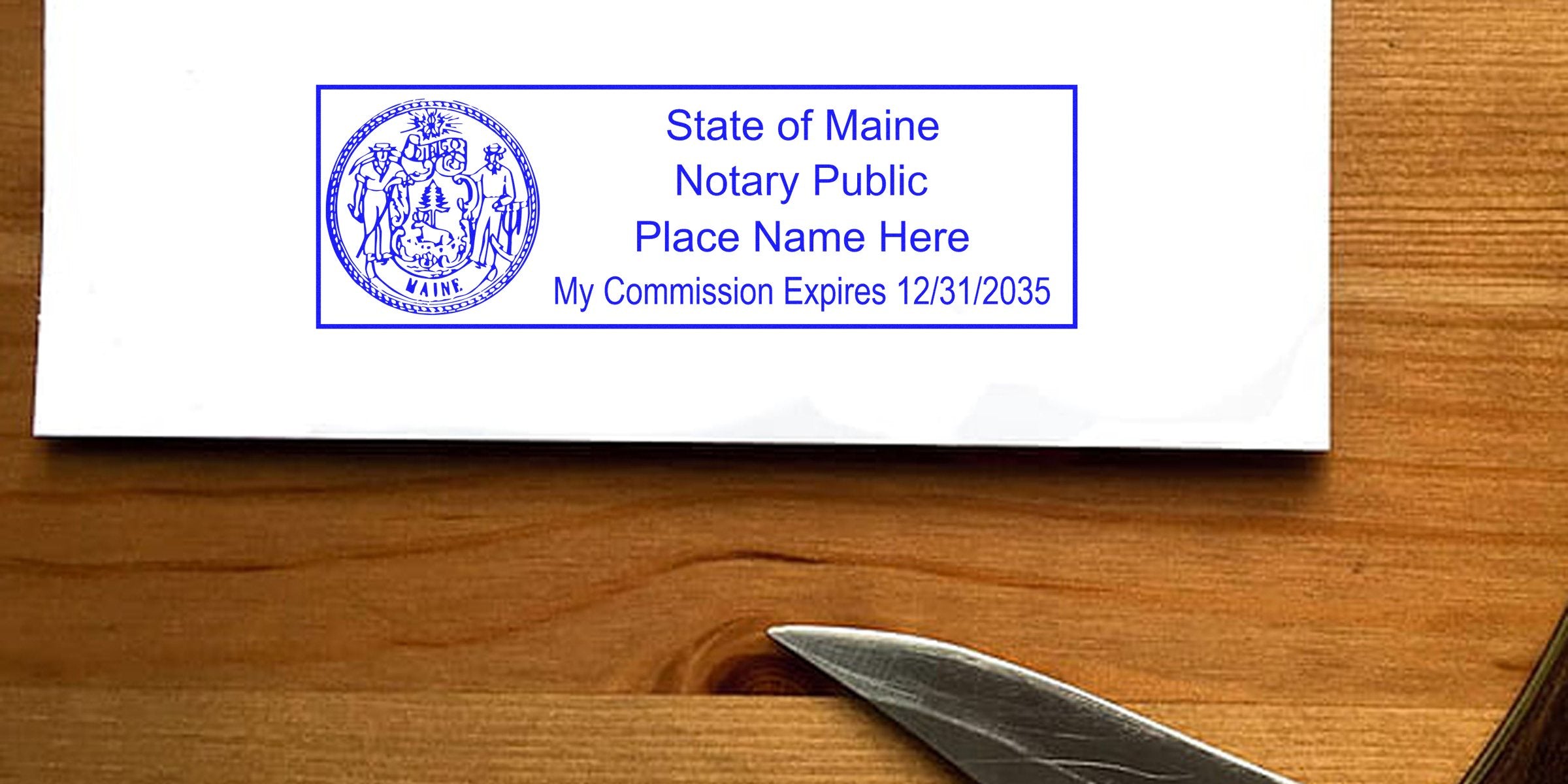Envelope on a wooden table stamped with a blue "State of Maine Notary Public" seal and commission expiration date, with a pair of metal scissors visible at the edge.