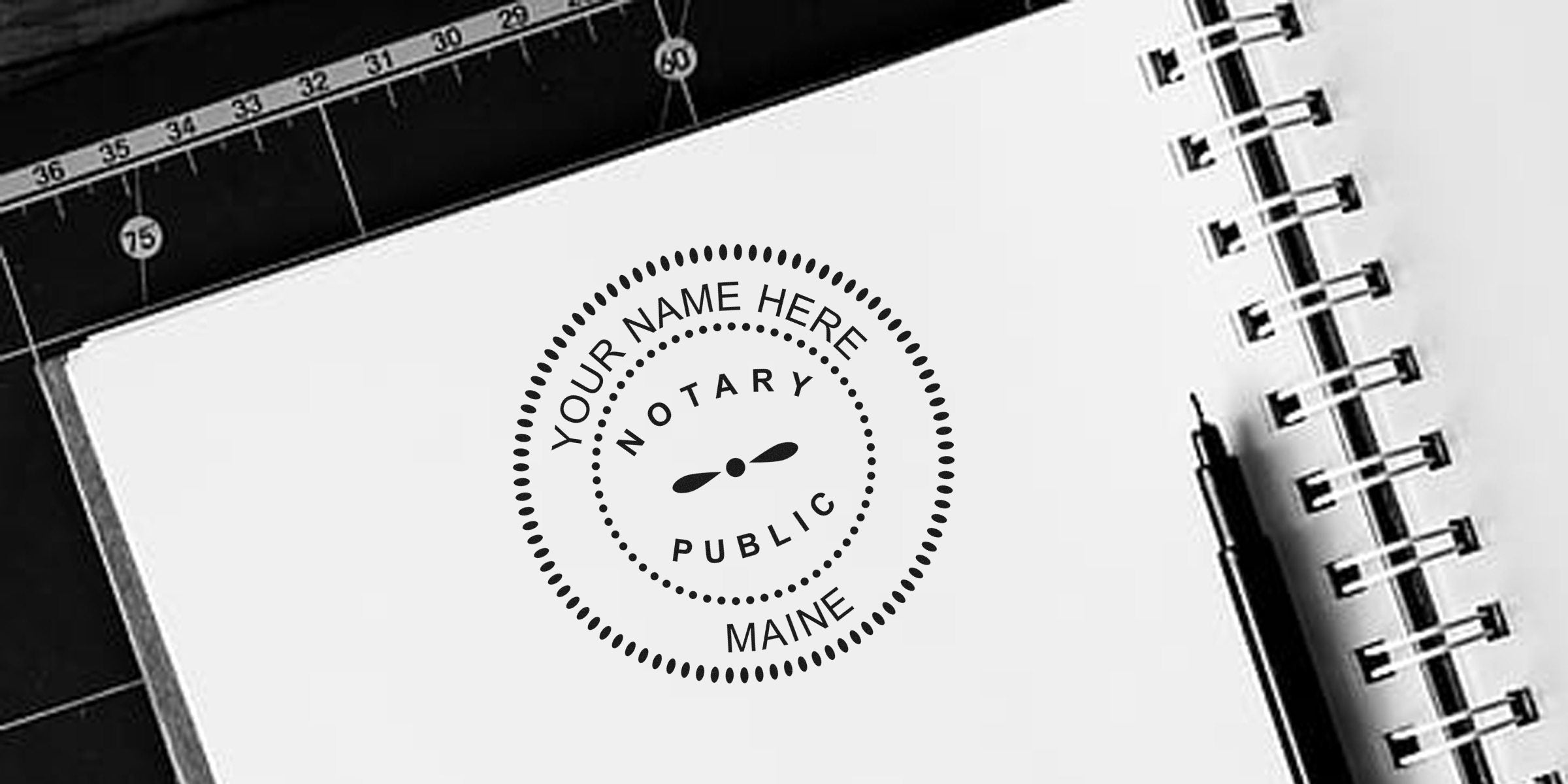 Black-and-white mockup of a circular "Notary Public" stamp reading "Your Name Here, Maine" on white paper next to a spiral notebook, pen, and cutting mat with ruler markings — notary stamp design mockup for legal branding.