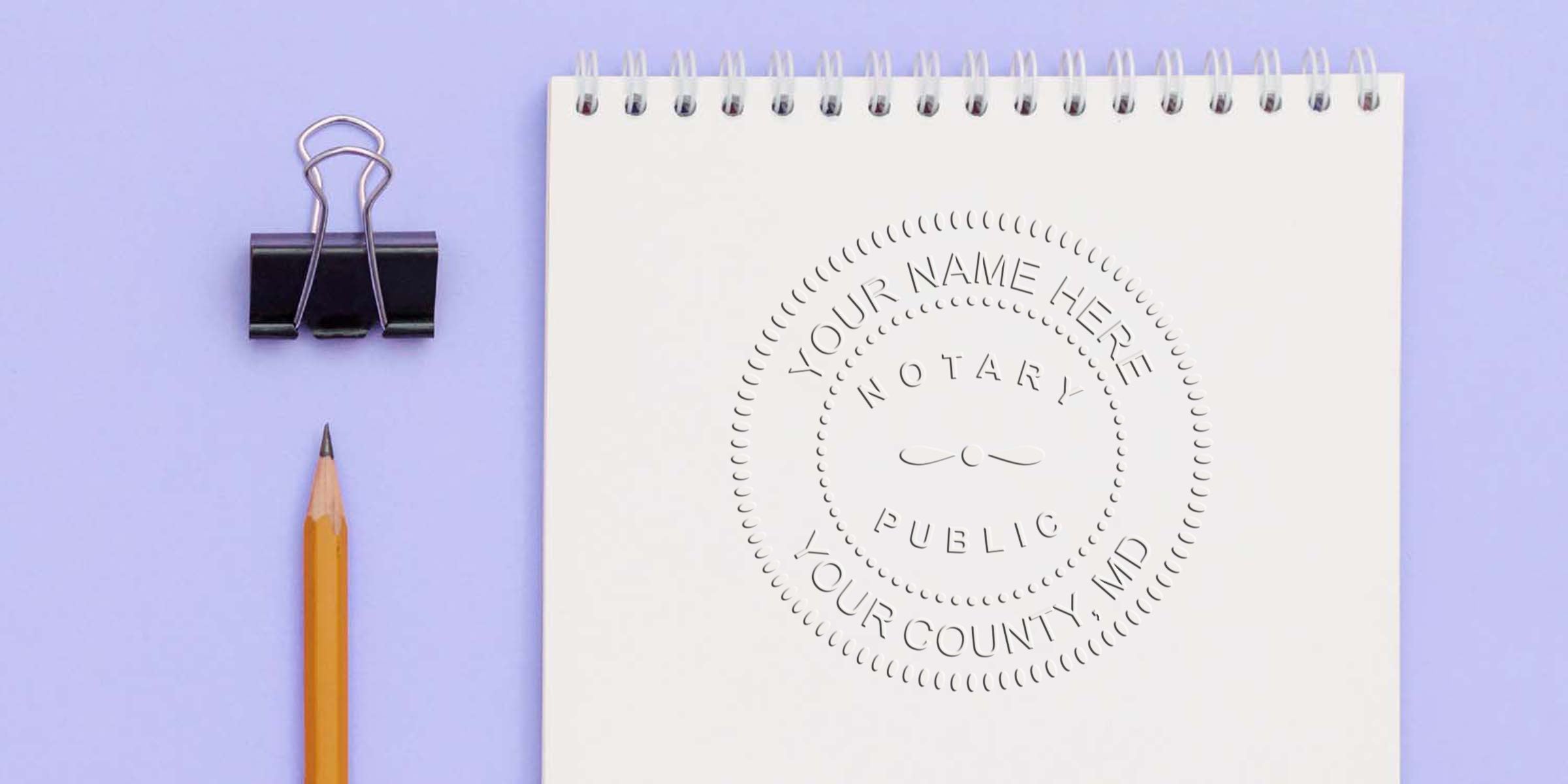 Top-down photo of a spiral white notepad embossed with a circular notary public seal on a lavender background, next to a yellow pencil and black binder clip.