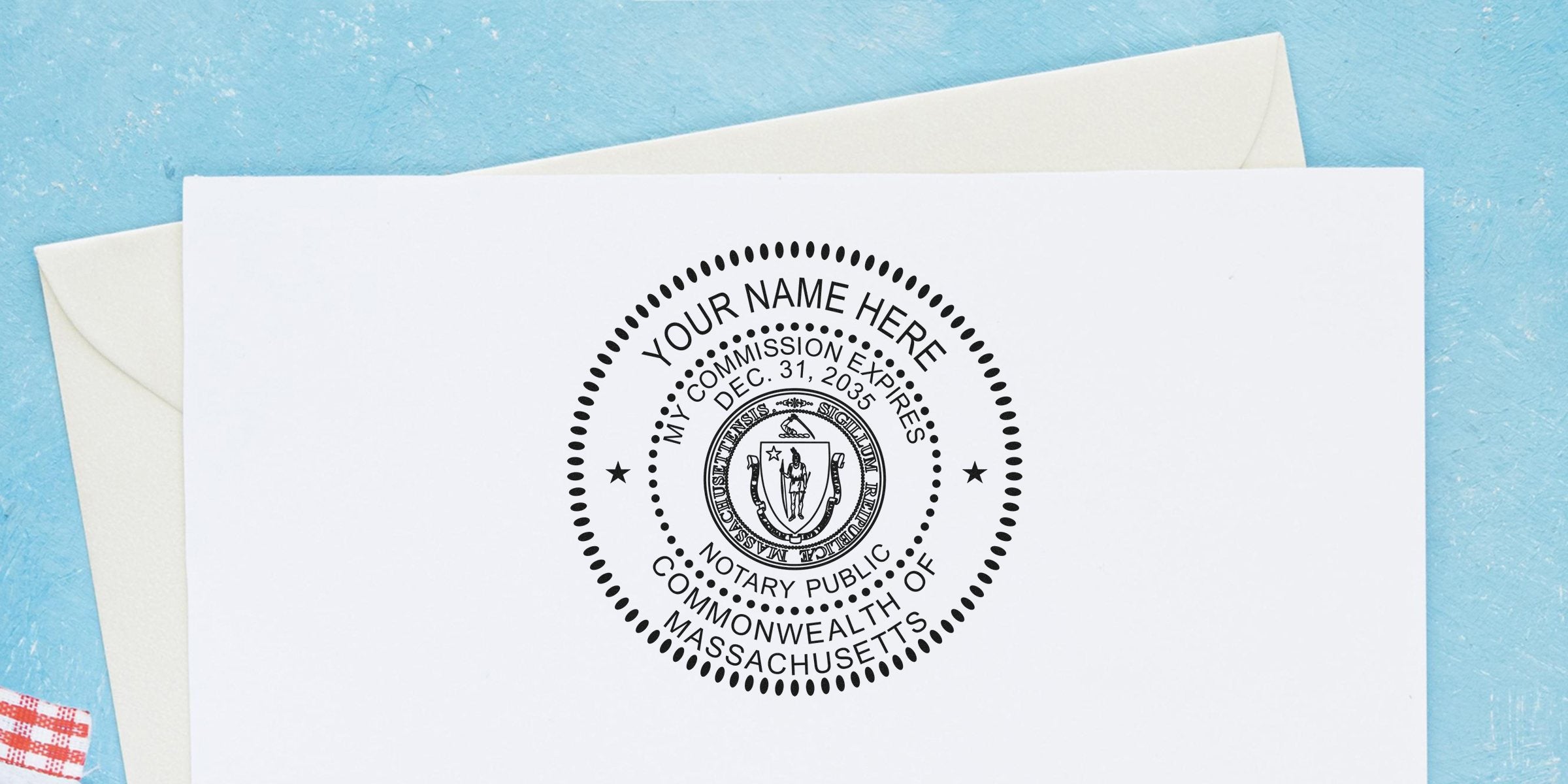 Close-up of a round Massachusetts notary public seal stamped on white paper showing customizable "Your Name Here," commission expiry Dec. 31, 2035, decorative dotted border and state emblem, on a light blue background with an envelope.
