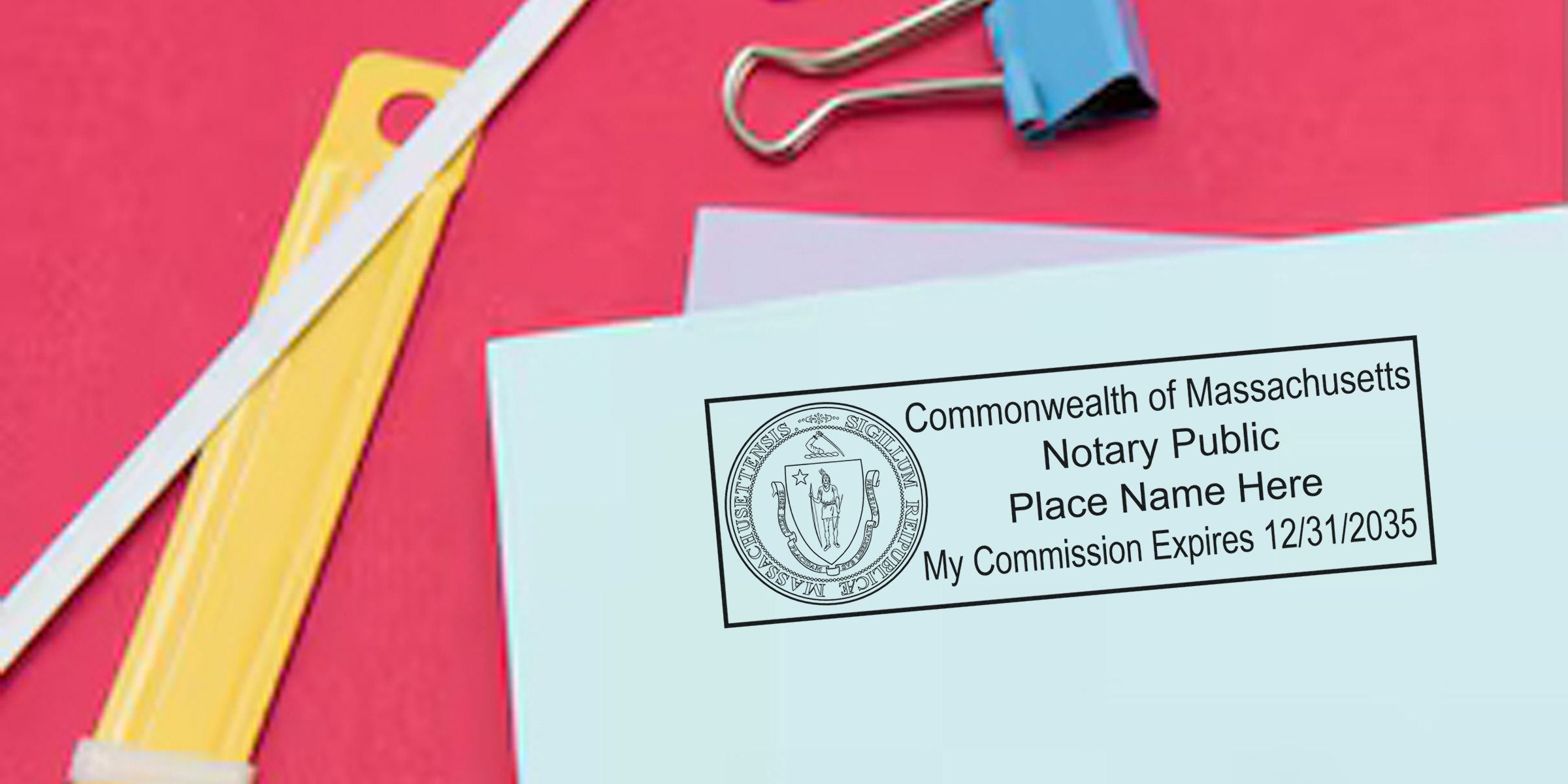 Envelope with Commonwealth of Massachusetts notary public stamp and commission expiration date, pastel papers, blue binder clip and yellow utility knife on pink background