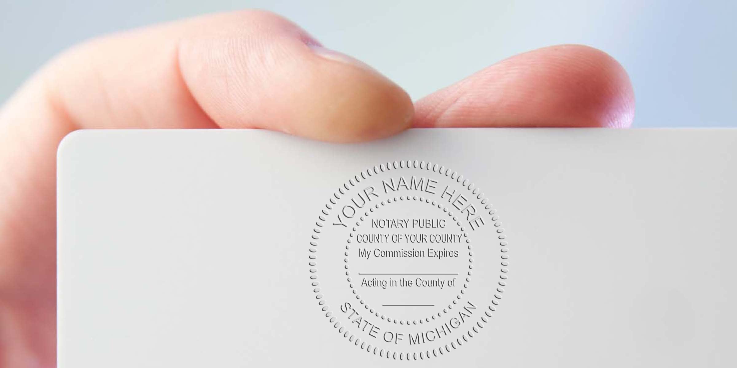 Close-up of a hand holding a white business card embossed with a circular notary public seal reading "Your Name Here" and "State of Michigan" — notary embossing, professional seal on business card, verification badge.