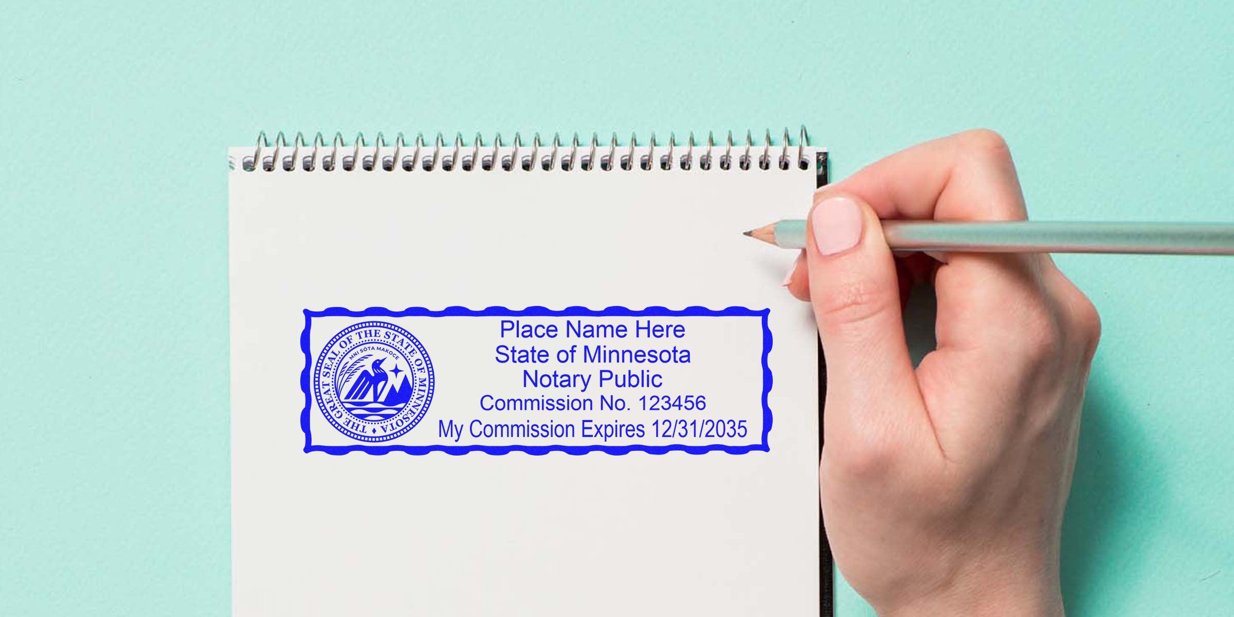 Spiral notebook page with blue Minnesota Notary Public stamp template showing state seal, placeholder name, commission number and expiration date, right hand holding pencil over light teal background