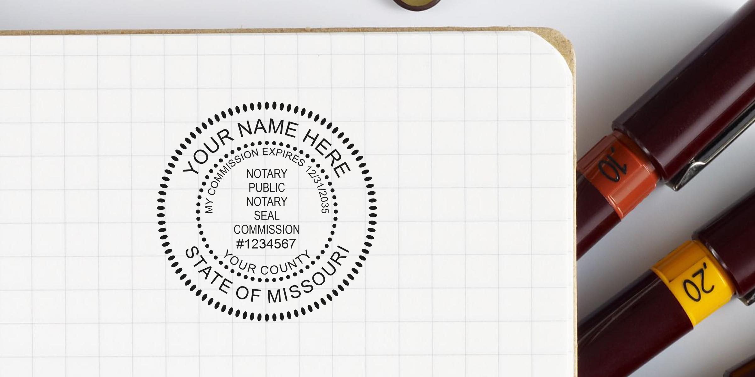 Notary public circular seal mockup stamped on graph notebook page showing customizable name, county and State of Missouri commission details, with two maroon fountain pens labeled "10" and "20" beside the notebook.