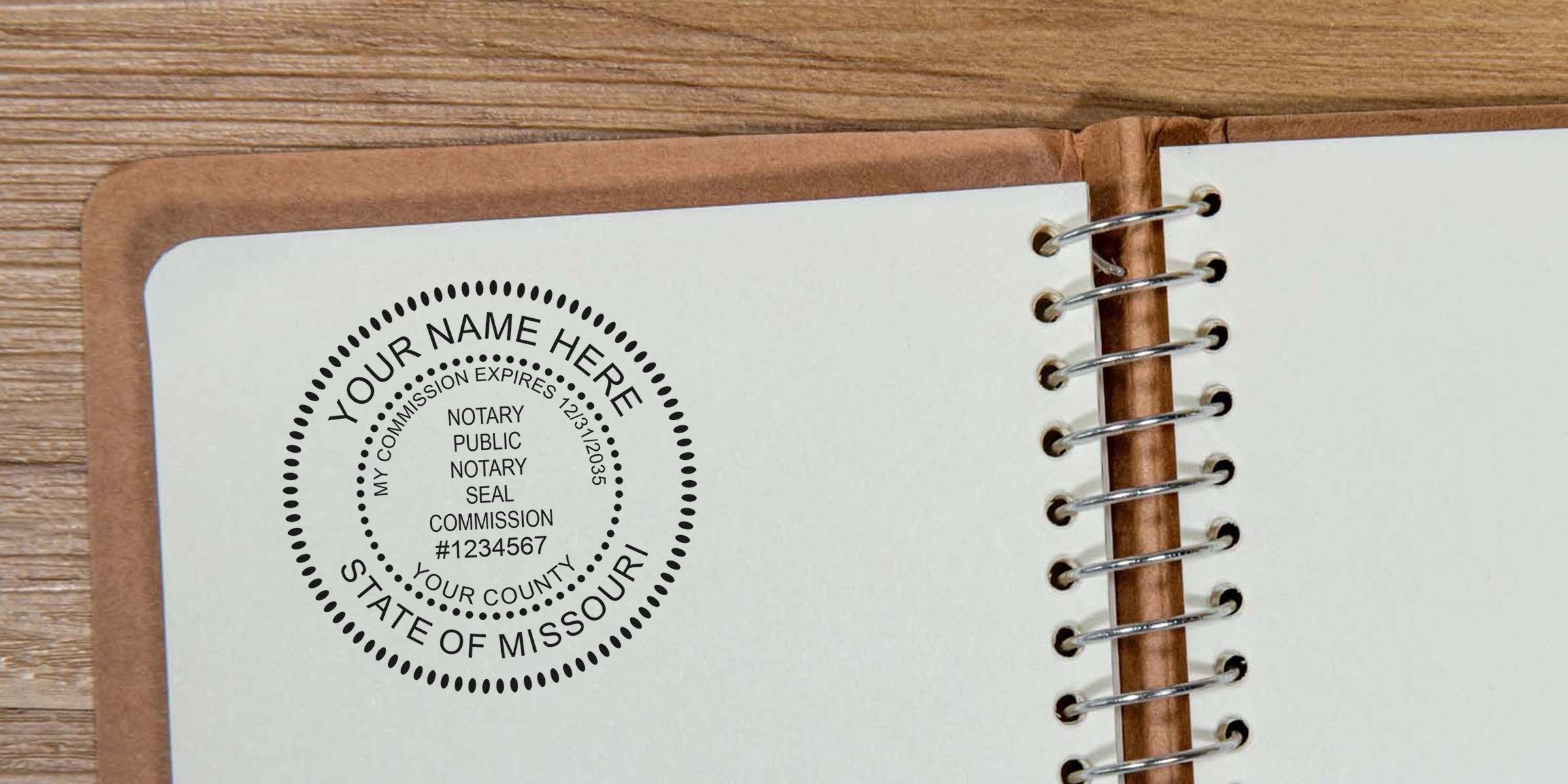 Open spiral notebook on wooden desk showing blank white page stamped with circular Missouri notary public seal mockup reading "Your Name Here" and sample commission number.