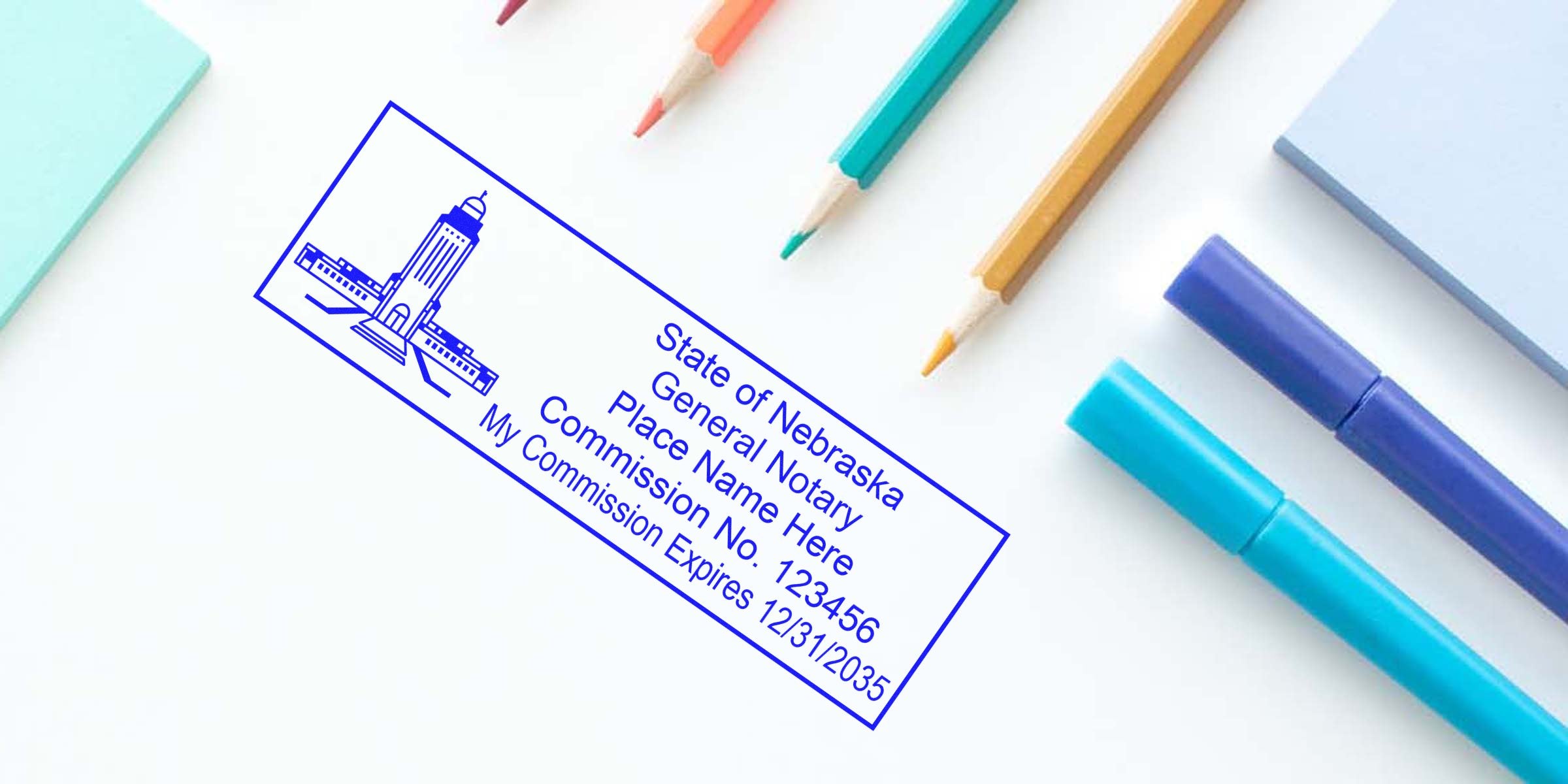 Blue Nebraska notary stamp impression reading "State of Nebraska General Notary" on white desk surrounded by colored pencils, markers and sticky notes — notary seal and commission info.