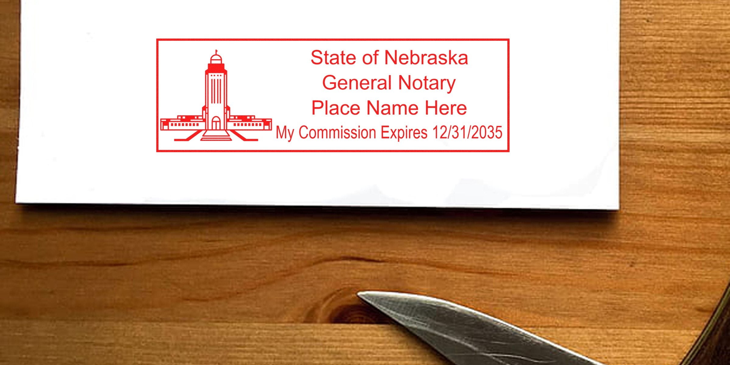 Red State of Nebraska general notary stamp on white envelope showing capitol building icon, placeholder name and commission expiration date "12/31/2035", placed on a wooden desk with a metal letter opener.