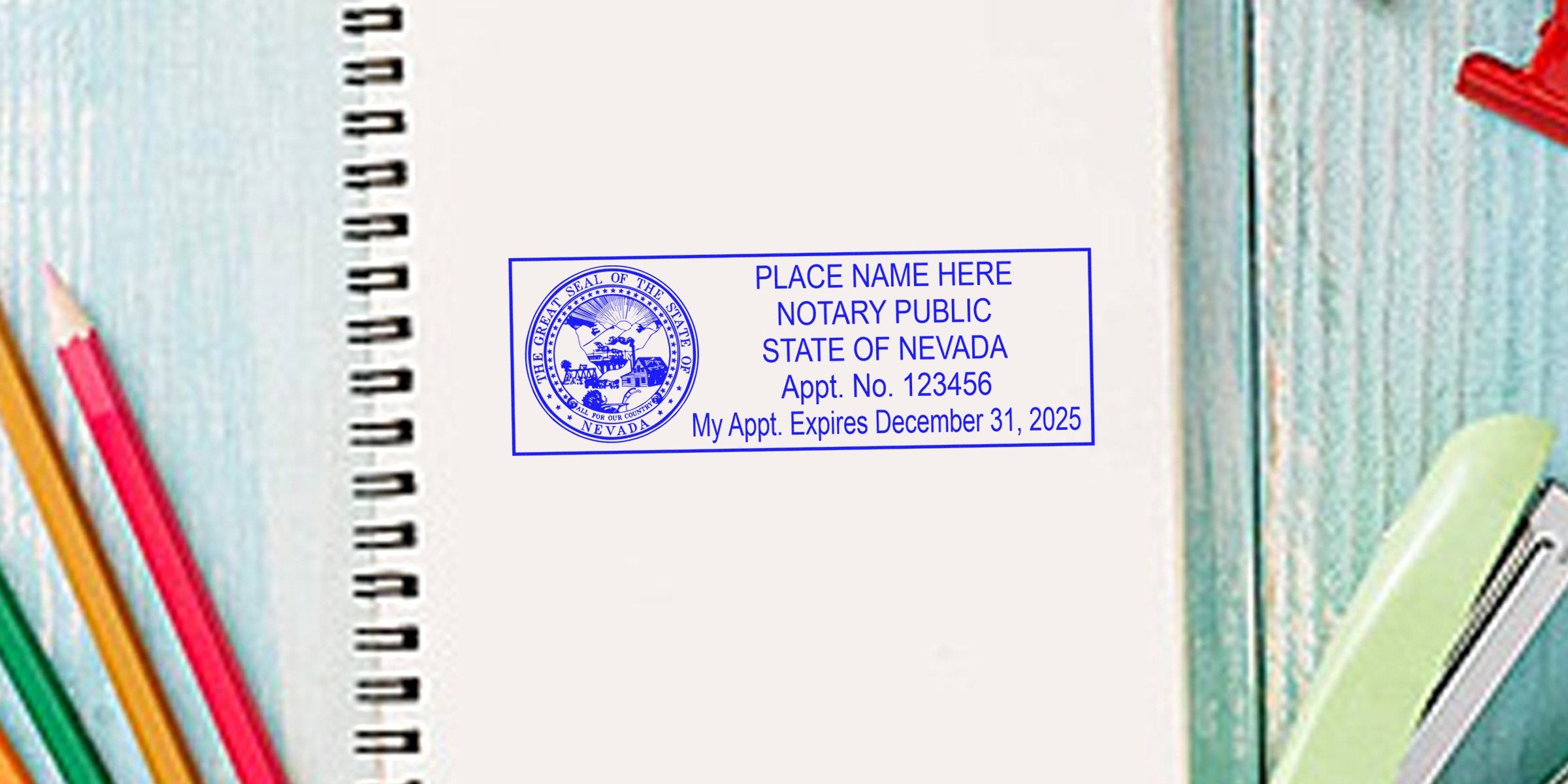 Blue rectangular Nevada notary public stamp on open spiral notebook reading "PLACE NAME HERE, Appt. No. 123456, Expires December 31, 2025" with colored pencils and stapler nearby